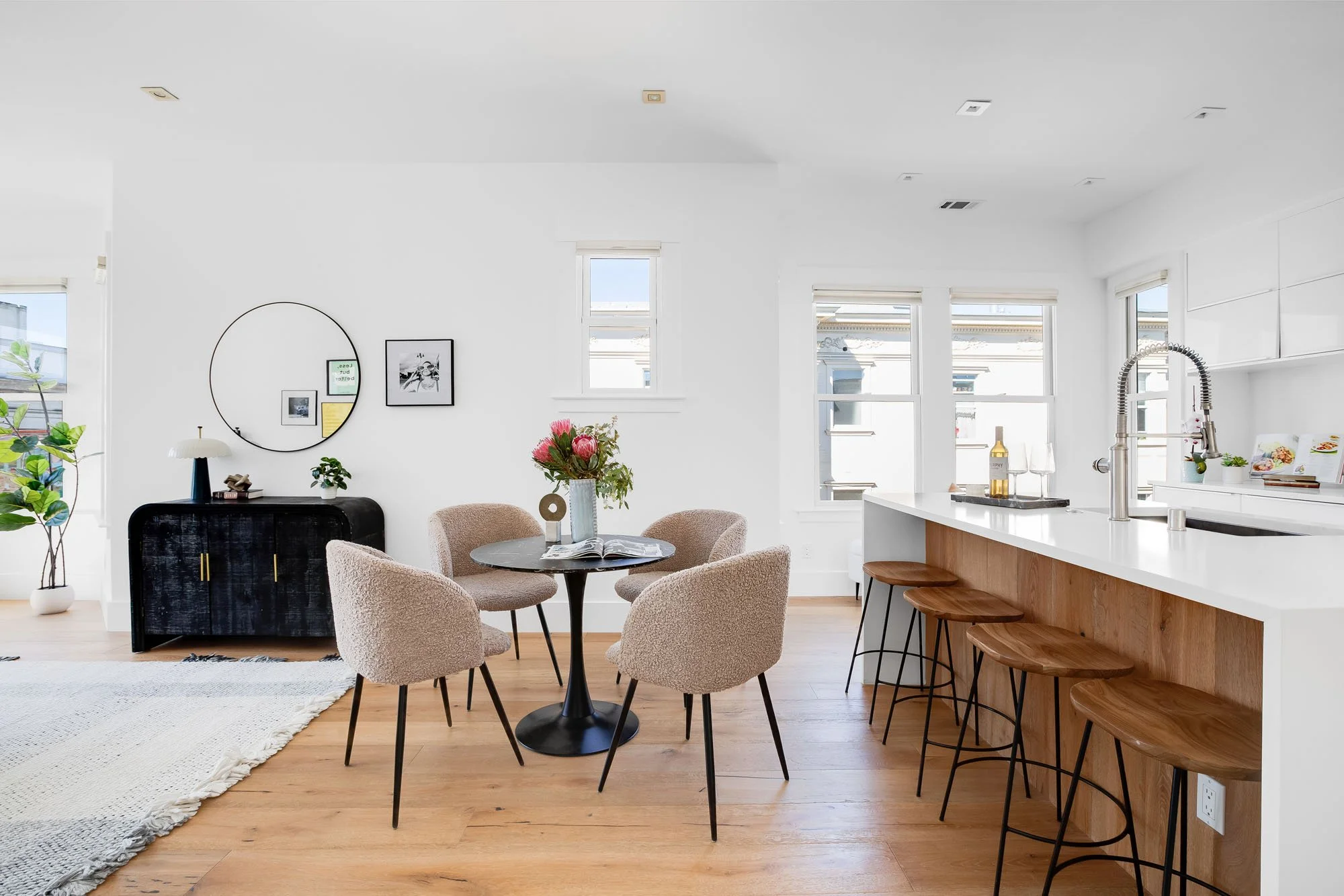 Contemporary kitchen island with wood paneling and four wooden bar stools adjacent to a stylish dining area.