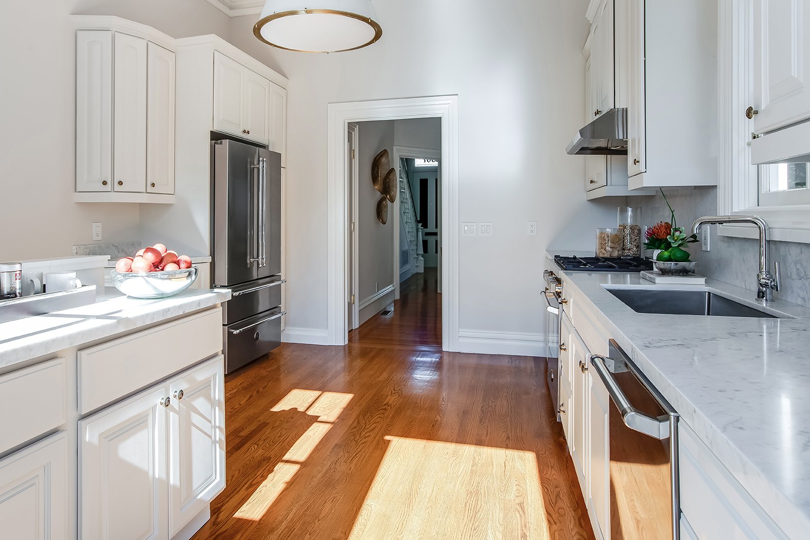 Renovated chef's kitchen featuring Carrera marble countertops, custom white cabinetry, and a high-end stainless steel French door refrigerator.