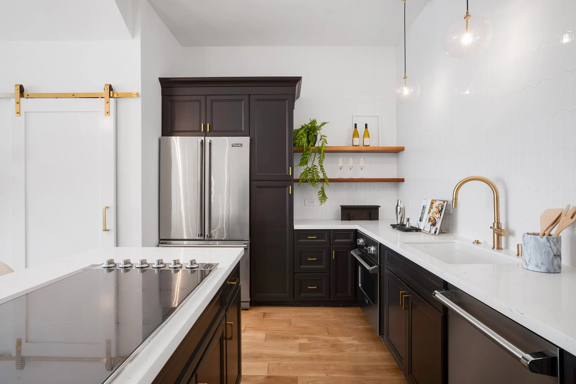 Luxury kitchen at 4545 18th Street San Francisco TIC featuring Viking stainless steel French door refrigerator, espresso Shaker cabinets with brass hardware, white quartz countertops, walnut open shelving, gold sliding barn door, and induction cookto
