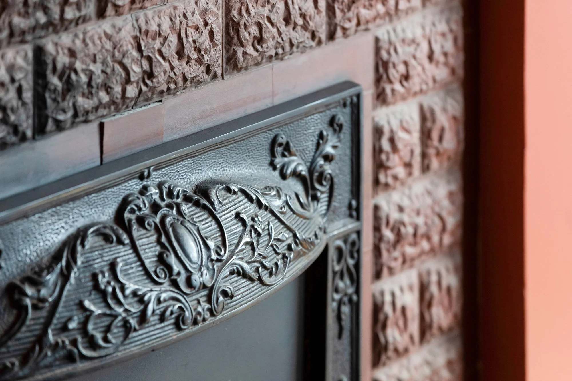 Close-up of original Victorian cast iron fireplace surround with ornate scrollwork and decorative ceramic tile surround in Presidio Heights Victorian flat, San Francisco