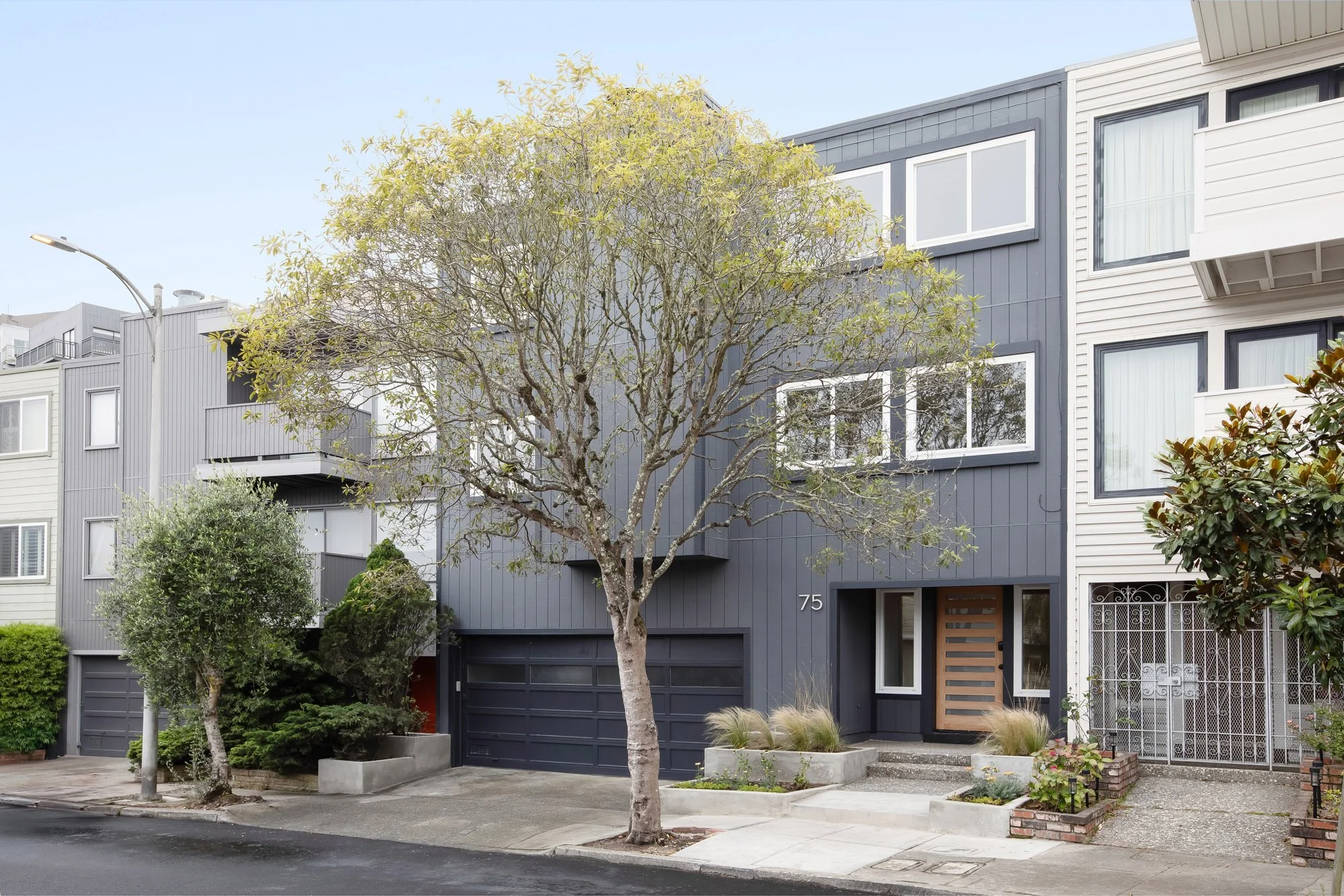 75 Aloha Avenue, a gray vertical-board single-family home in San Francisco's Golden Gate Heights, with a two-car garage and mature street tree.