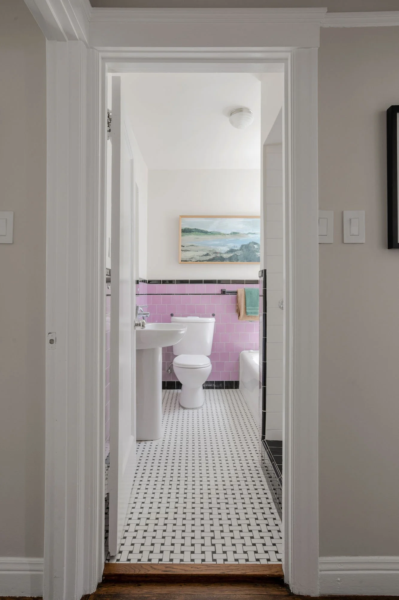 Classic San Francisco bathroom featuring vintage-style pink wall tiles, a black tile border, and a traditional white pedestal sink.
