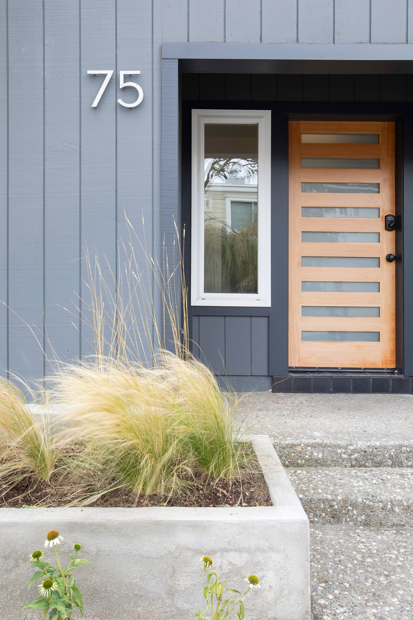 Front entry at 75 Aloha Avenue in Golden Gate Heights, with a natural wood door, frosted-glass panels, and a concrete planter of ornamental grasses.