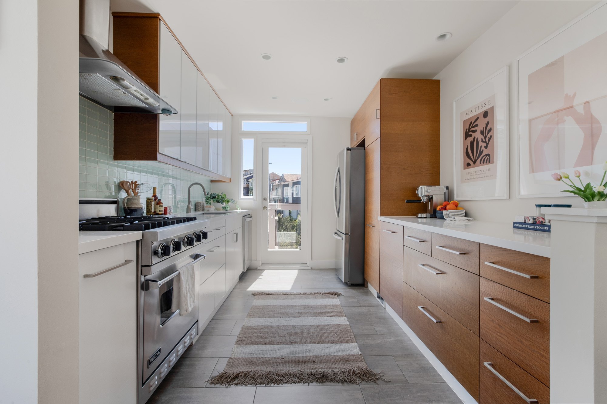 Modern galley kitchen featuring a professional Viking gas range, stainless steel appliances, and sleek wood cabinetry.