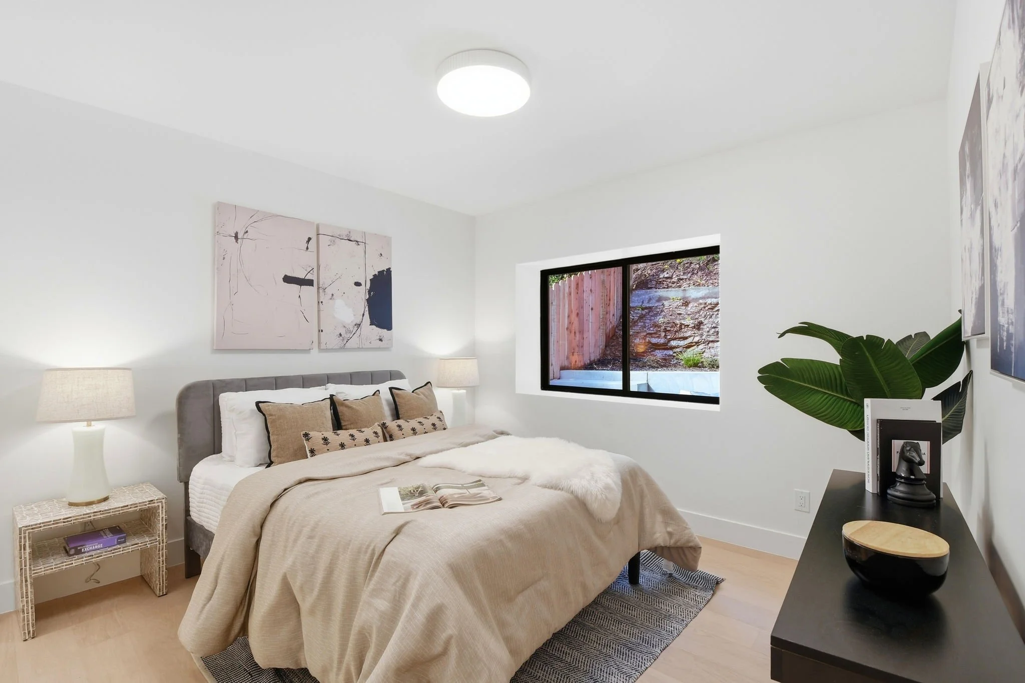 Modern guest bedroom in a Midtown Terrace residence featuring neutral earth tones, abstract canvas art, and high-end interior staging.