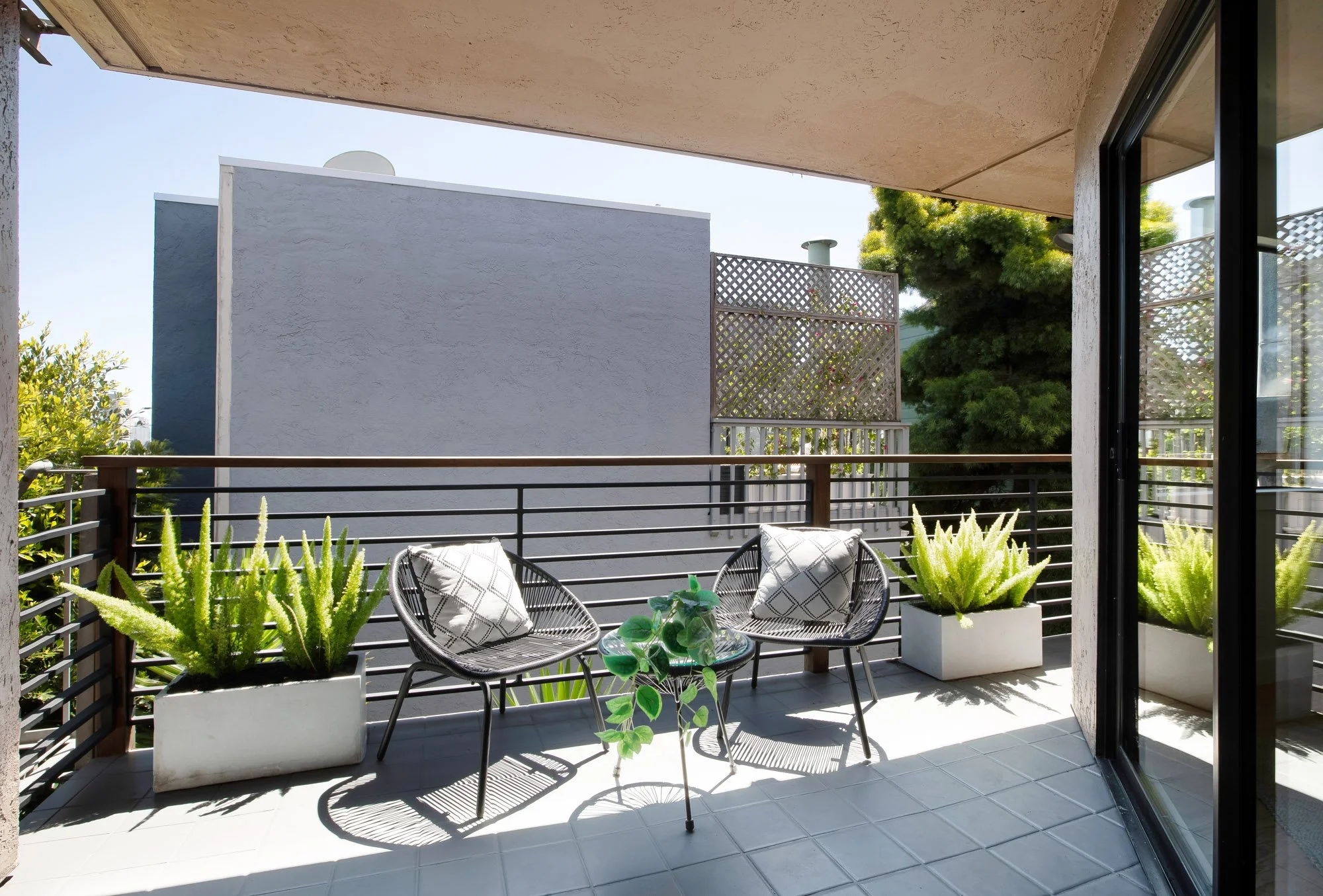 Sun-filled private balcony at 932 Broderick Street #2 with outdoor seating, planter boxes, and a privacy screen.