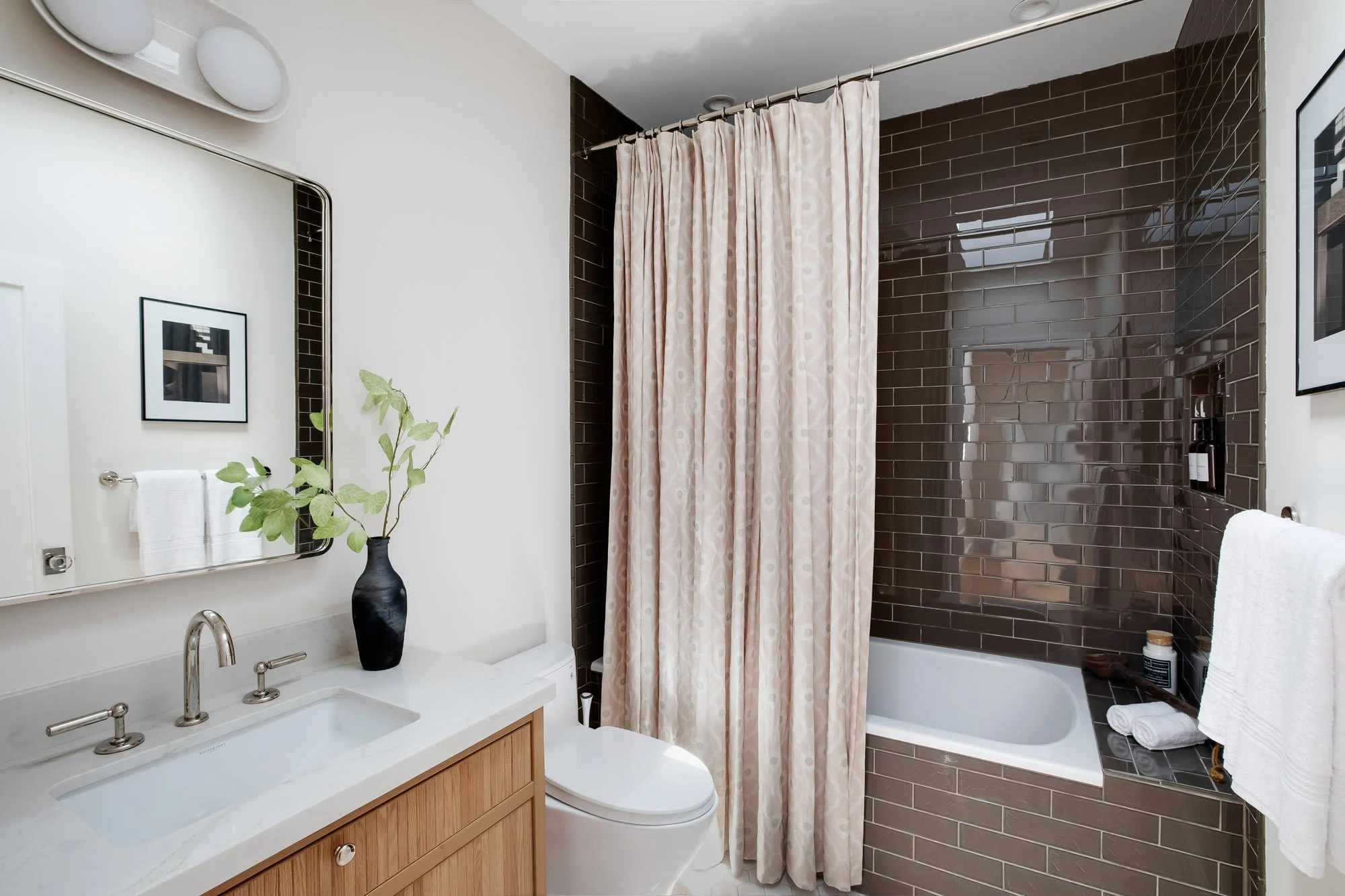 Renovated full bath at 771 Elizabeth Street featuring a glossy brown Fireclay tiled tub-shower with built-in niche, a custom white oak vanity, marble countertop, and polished nickel fixtures. 