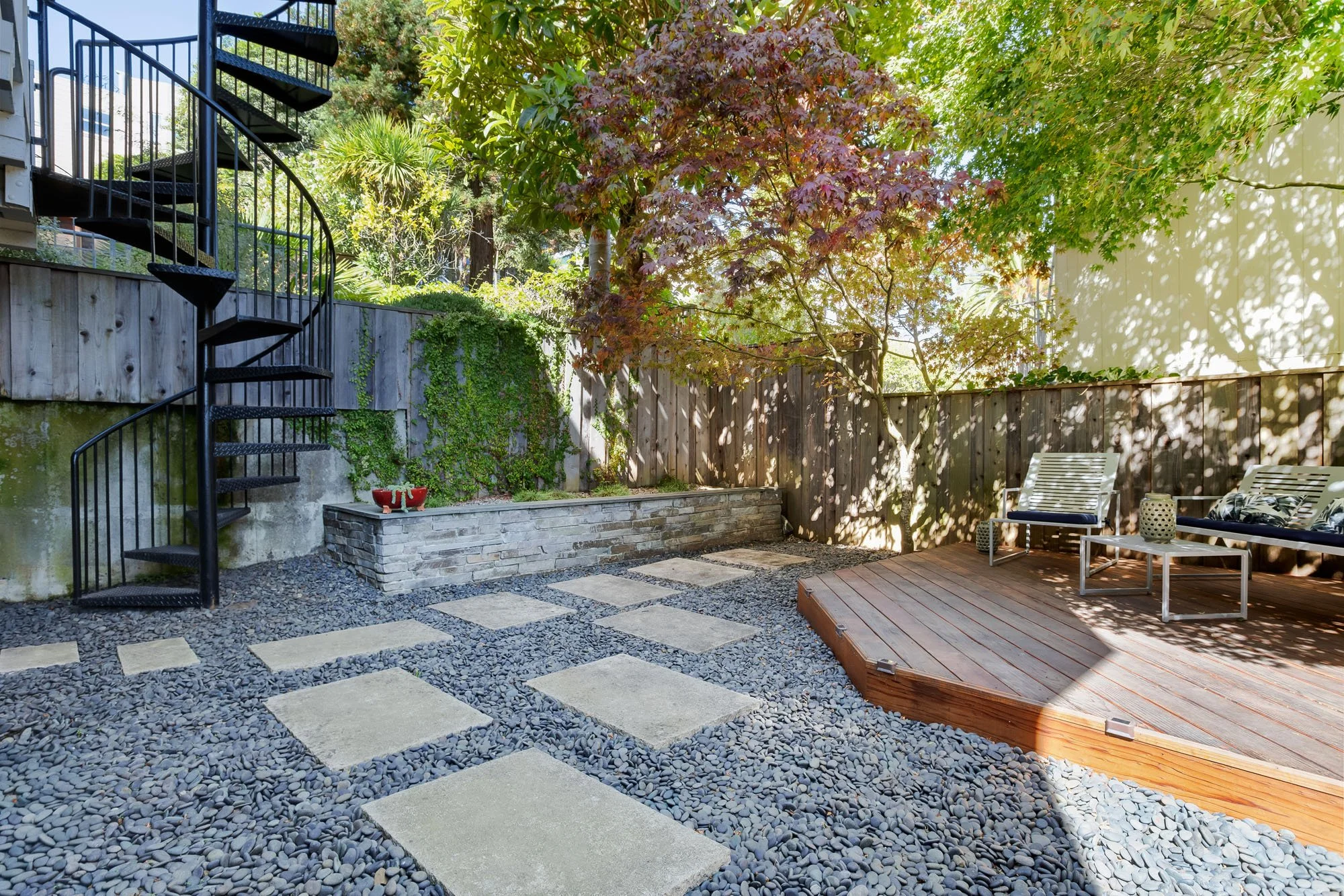 Wide-angle view of the tiered backyard garden at 144 Lower Terrace, highlighting the spiral staircase, stone masonry, and peaceful garden atmosphere.