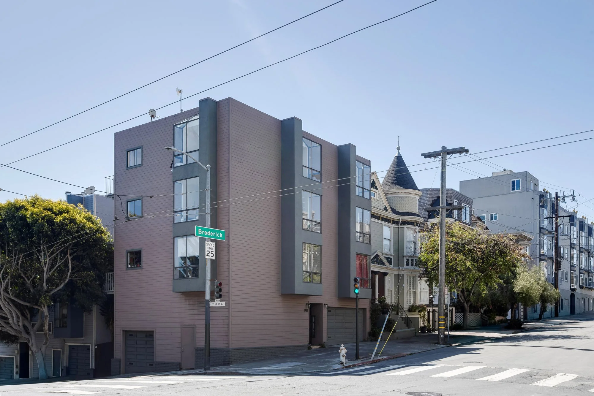 Exterior corner view of 932 Broderick Street, a modern multi-unit condo building in San Francisco's NoPa neighborhood, beside a Victorian home at the corner of Broderick and Turk.