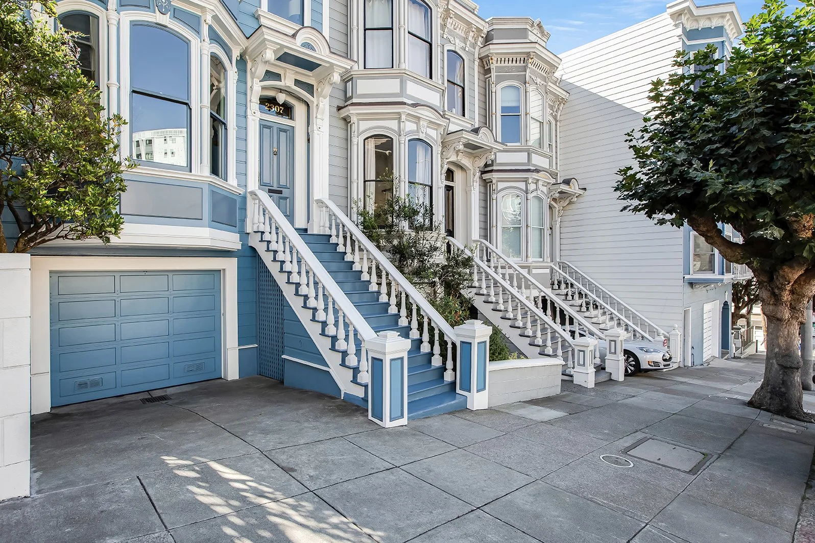 Street-level view of a renovated San Francisco Victorian house featuring a private attached garage and classic Italianate architecture.