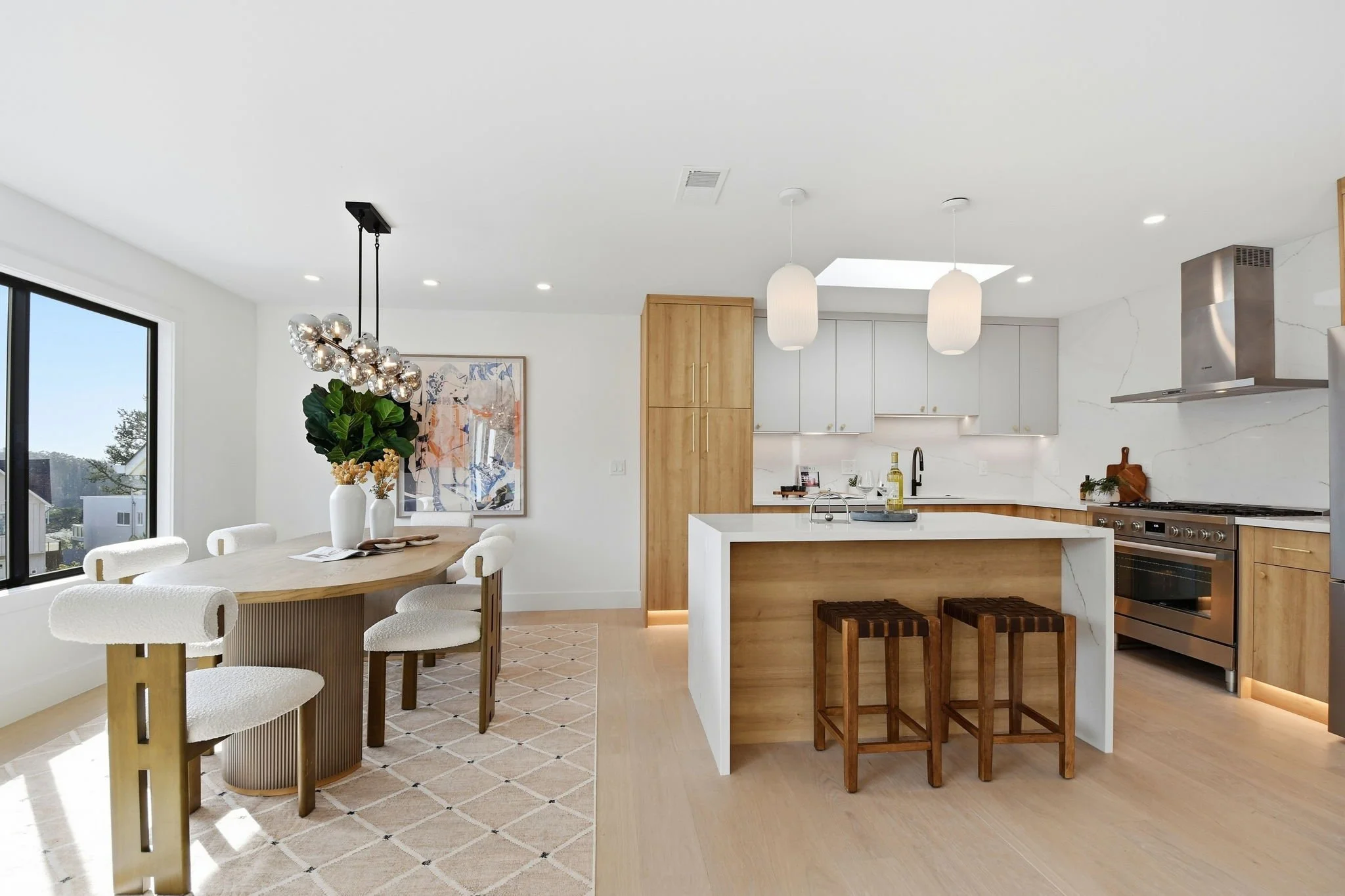 Sun-drenched kitchen and dining space in a Midtown Terrace home, highlighting the white marble backsplash and views of the San Francisco landscape.