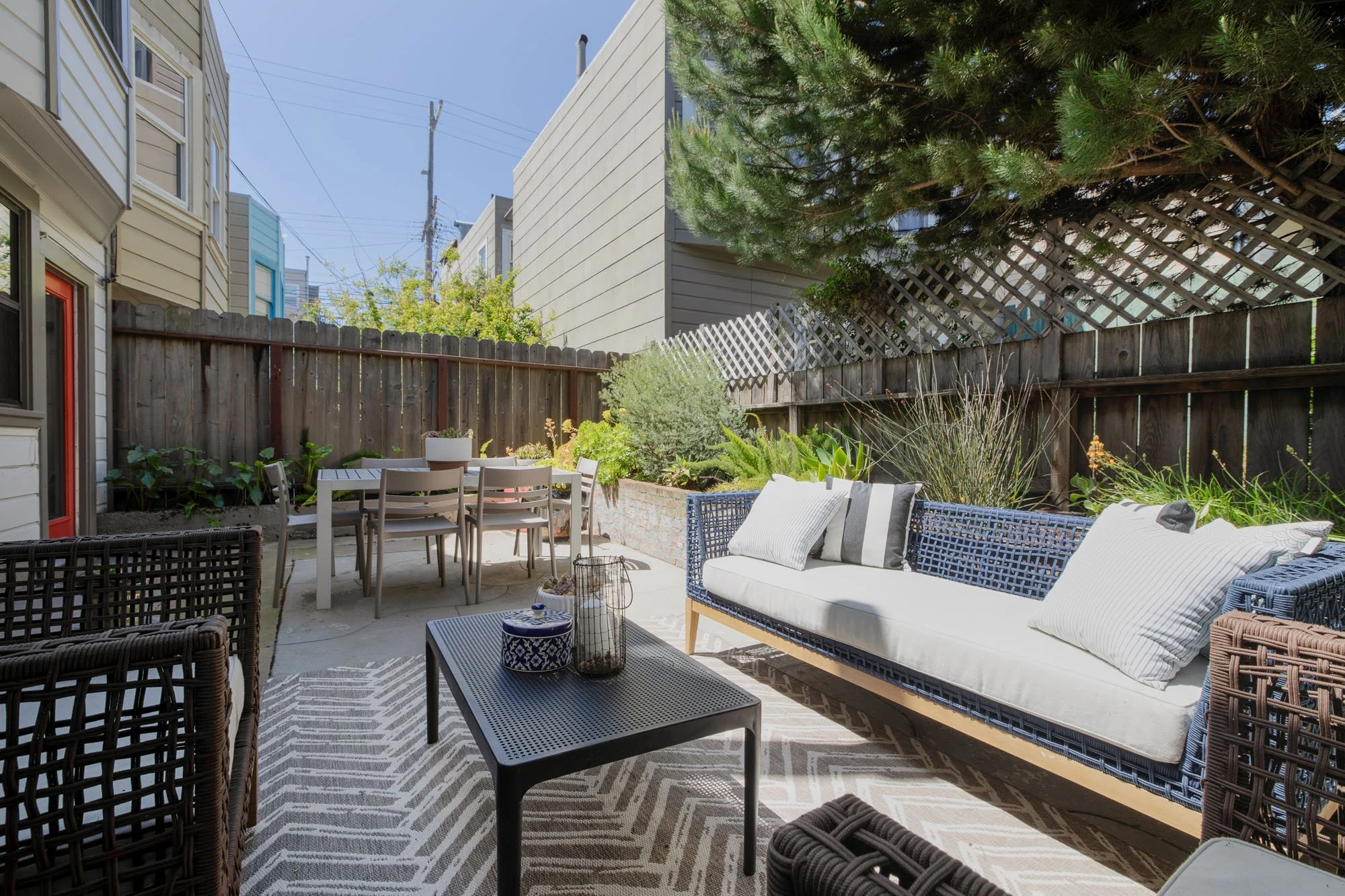 Private Mission District backyard patio at 2872 25th St featuring an outdoor dining set, modern wicker lounge seating, and a privacy fence.