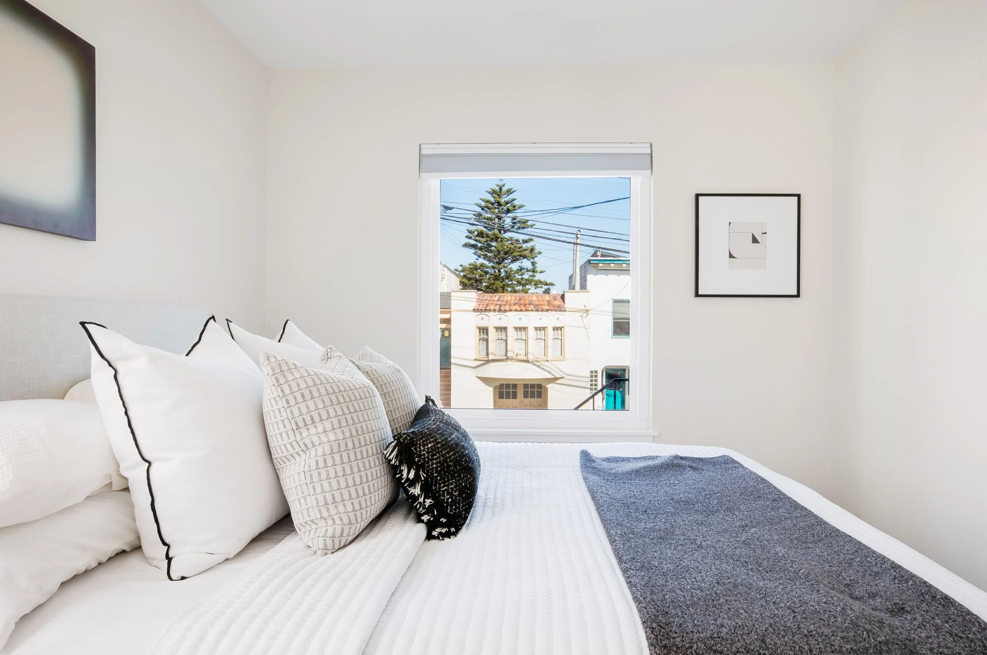 Bedroom at 465 30th Street with a new front-facing window looking out to a tile-roofed Mediterranean-style home and Norfolk pine across 30th Street