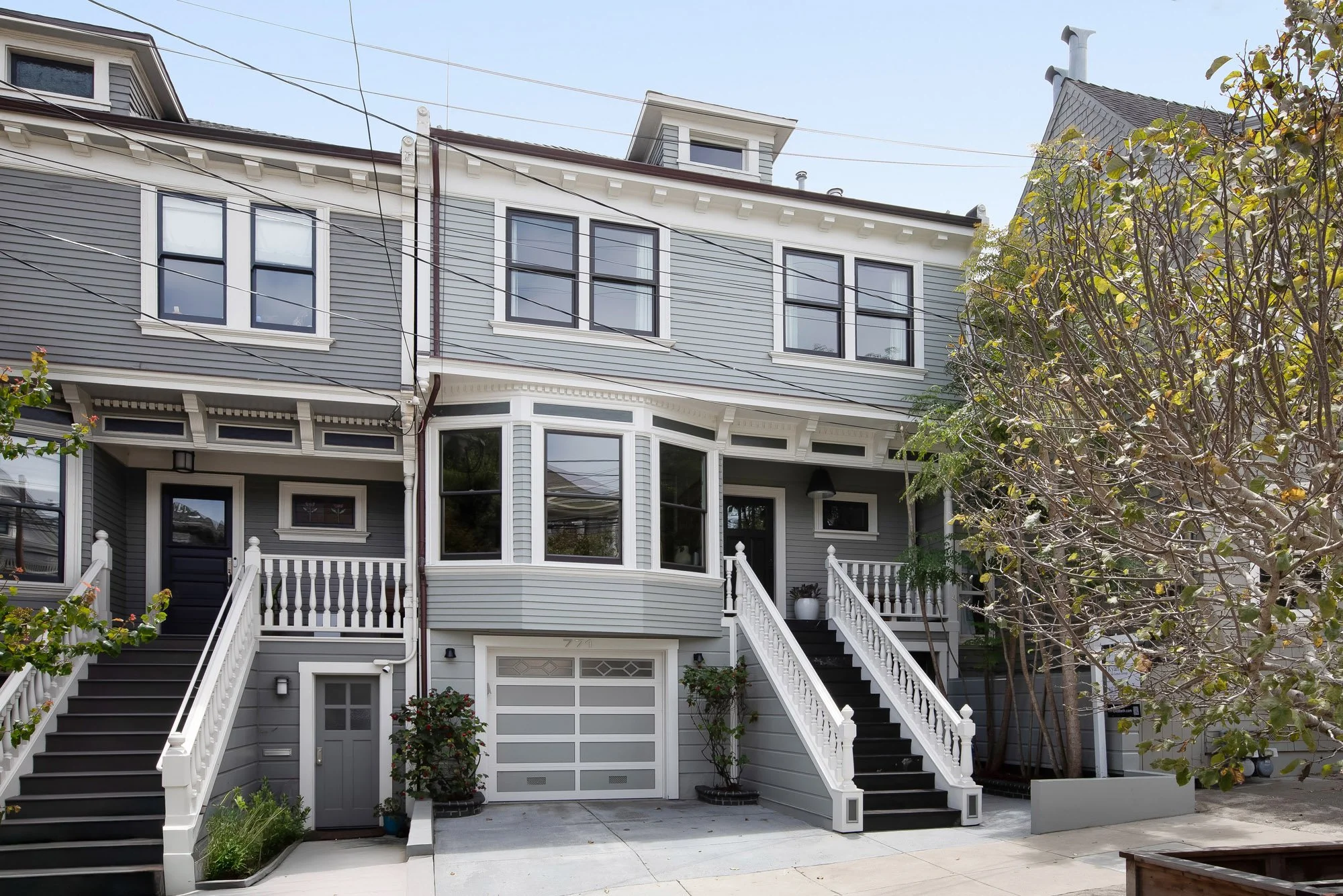 Front exterior of 771 Elizabeth Street, a grand Edwardian single-family home in Noe Valley, San Francisco, with gray siding, white trim, a classic bay window, twin staircases, and a one-car garage. #771Elizabeth #NoeValley #SanFranciscoRealEstate #Ed