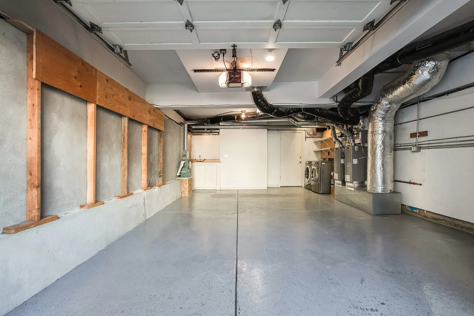 Spacious multi-car garage with concrete floors, laundry area, and modern HVAC systems in a renovated San Francisco residence.