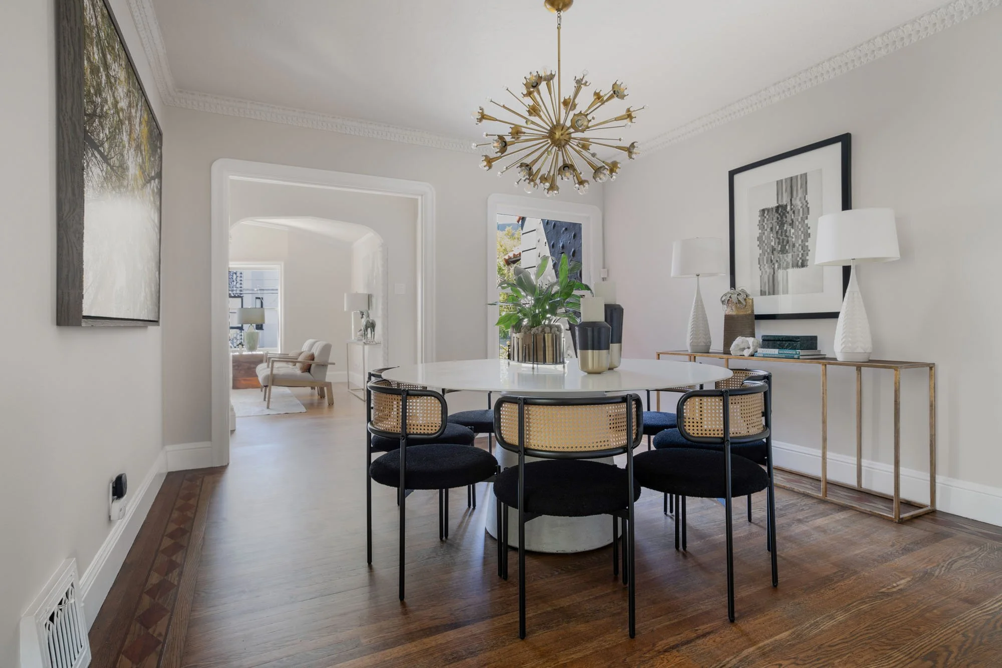 Open-concept dining area showing the seamless transition into the living room, highlighted by designer lighting and a neutral color palette.