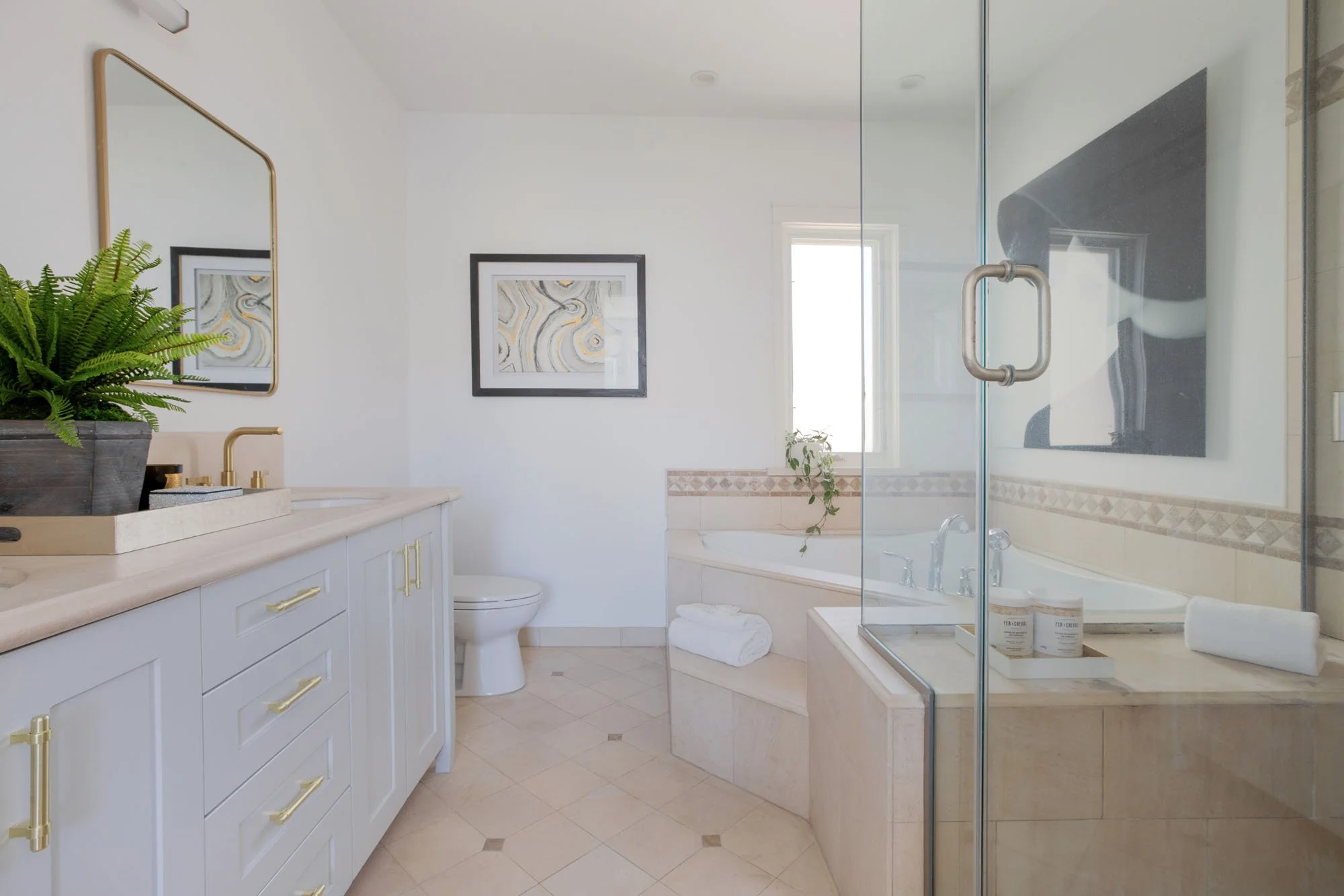 Contemporary master bedroom featuring a neutral color palette, a gold sunburst mirror above the headboard, and a stylish reading nook by the window.