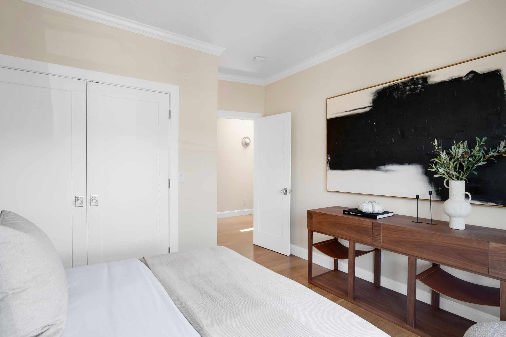 Bedroom at 771 Elizabeth Street in Noe Valley with floor-to-ceiling custom closets, a walnut console, large-scale black-and-white art, and warm hardwood floors.