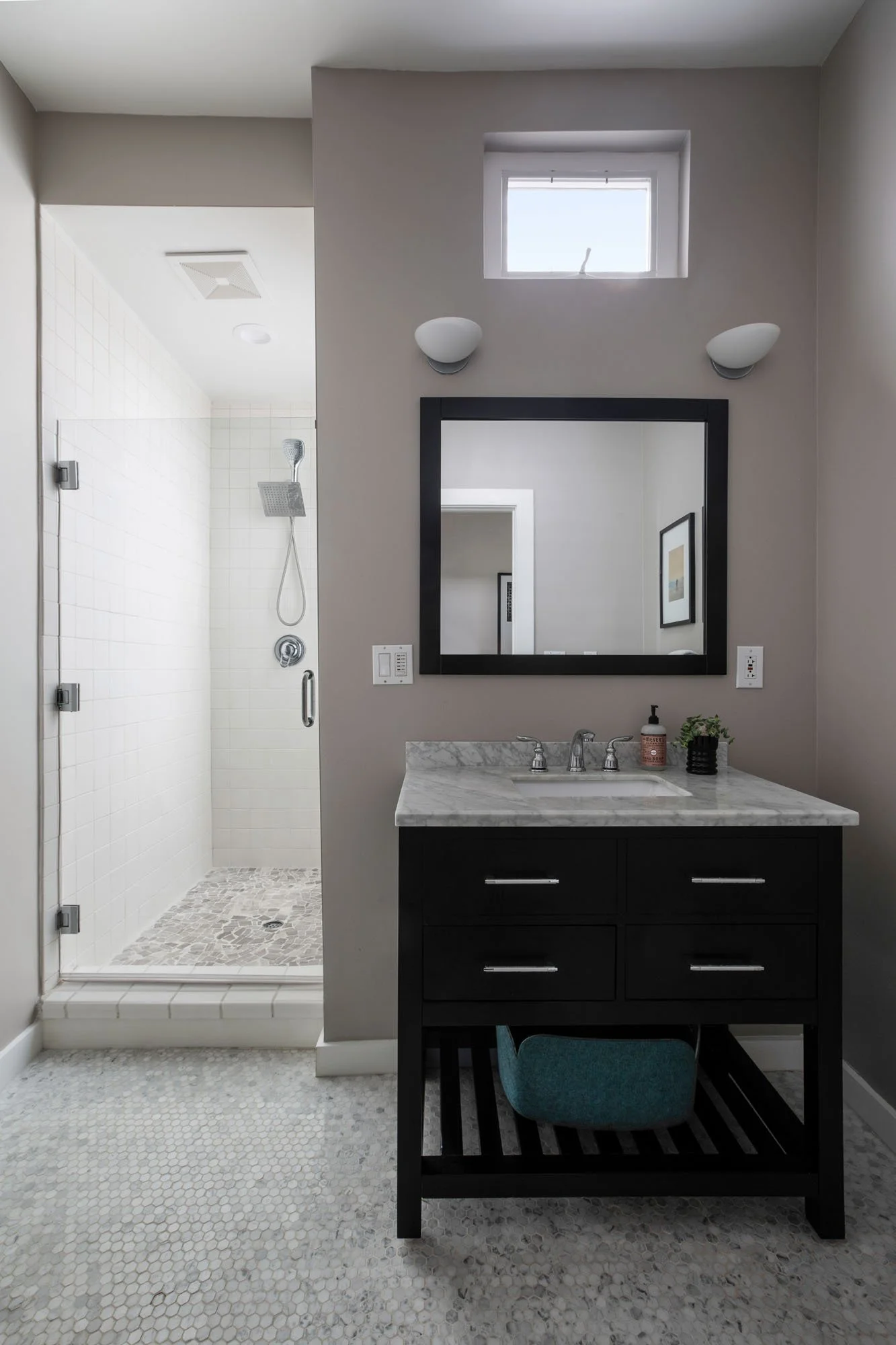 Contemporary bathroom with a dark wood vanity, marble countertop, penny tile flooring, and a walk-in shower with a rainfall showerhead.