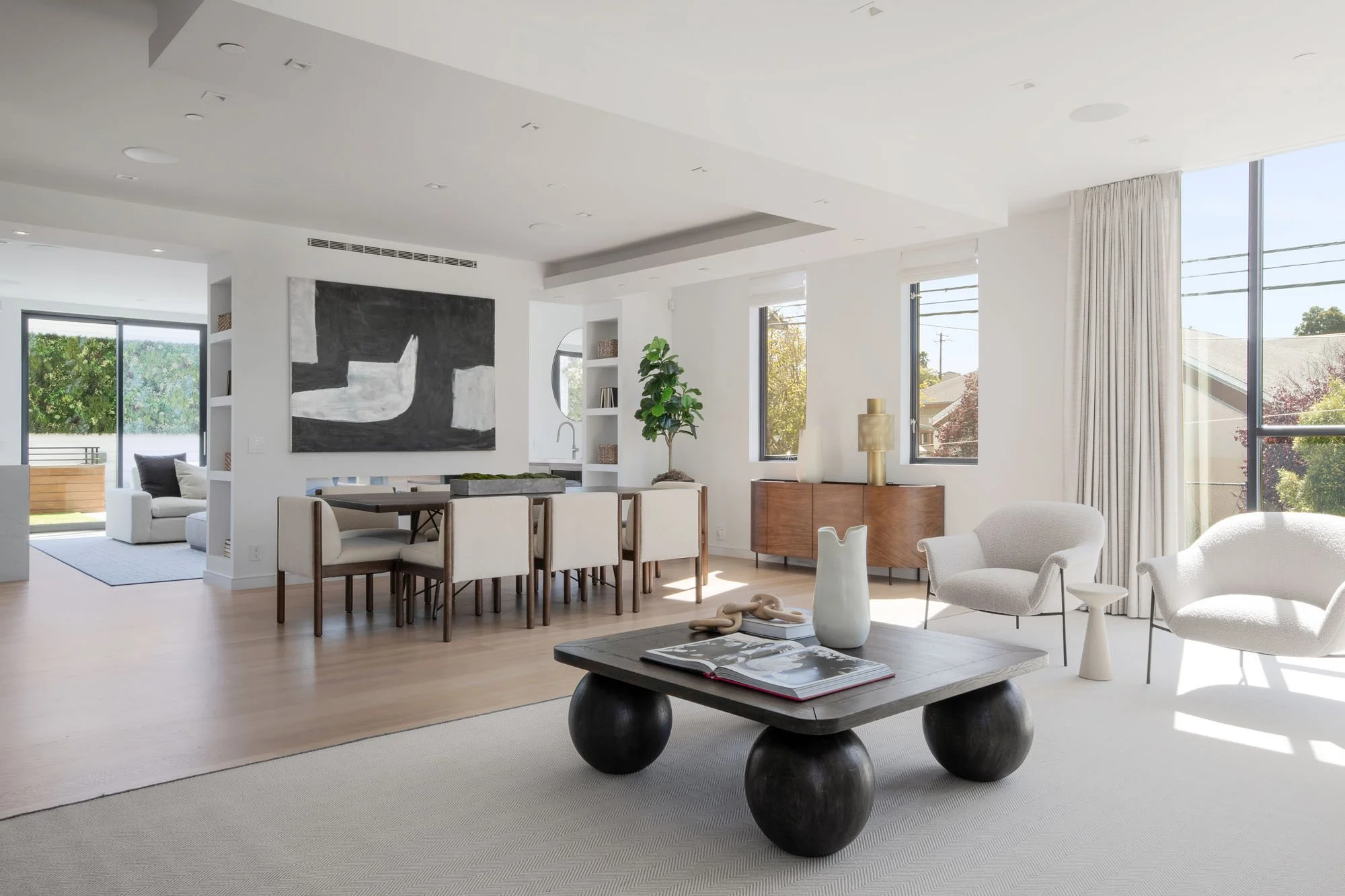 Sophisticated dining and living room transition at 1647 Sanchez, showcasing a large black-and-white abstract art piece, wooden sideboard, and light hardwood floors.