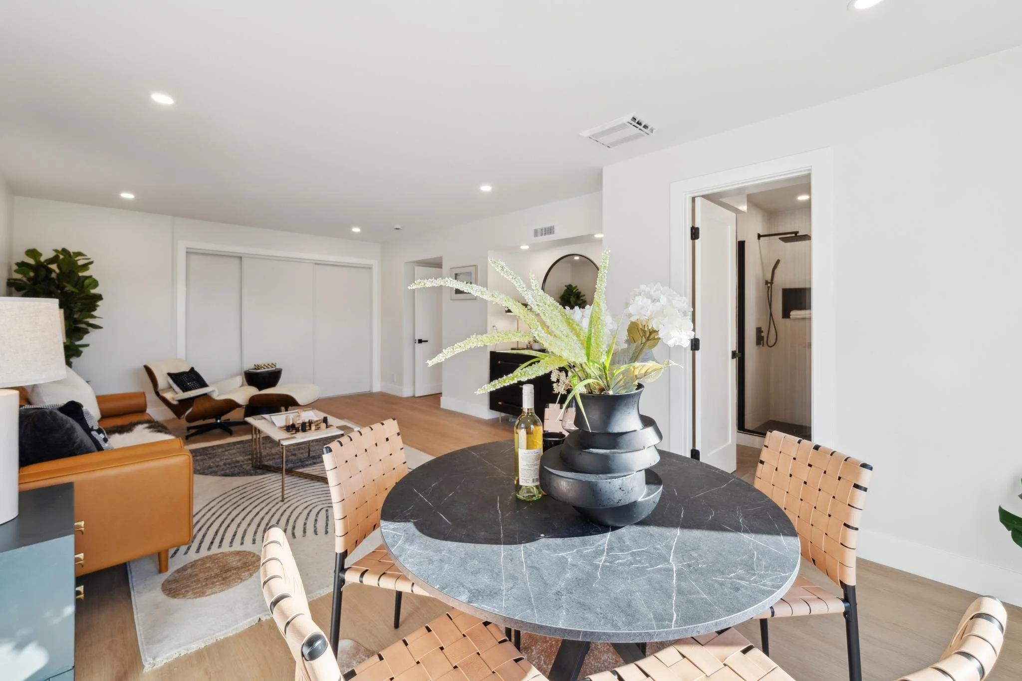 View from the dining nook toward the guest bathroom and living area, highlighting the modern, airy renovation of the home's lower level.