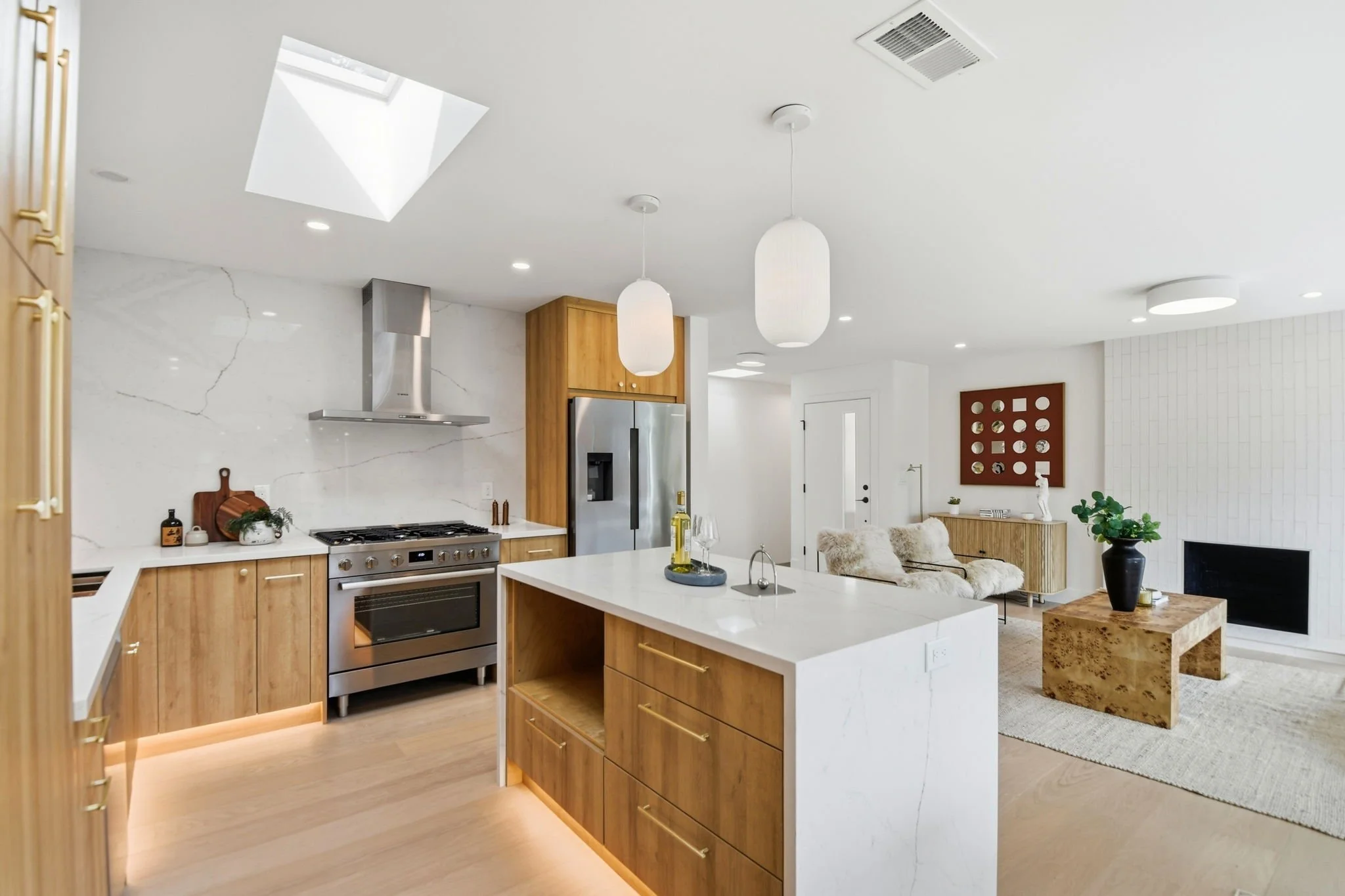 Detail shot of a luxury kitchen featuring a marble waterfall island with seating, integrated cabinetry, and high-end stainless steel refrigerator.
