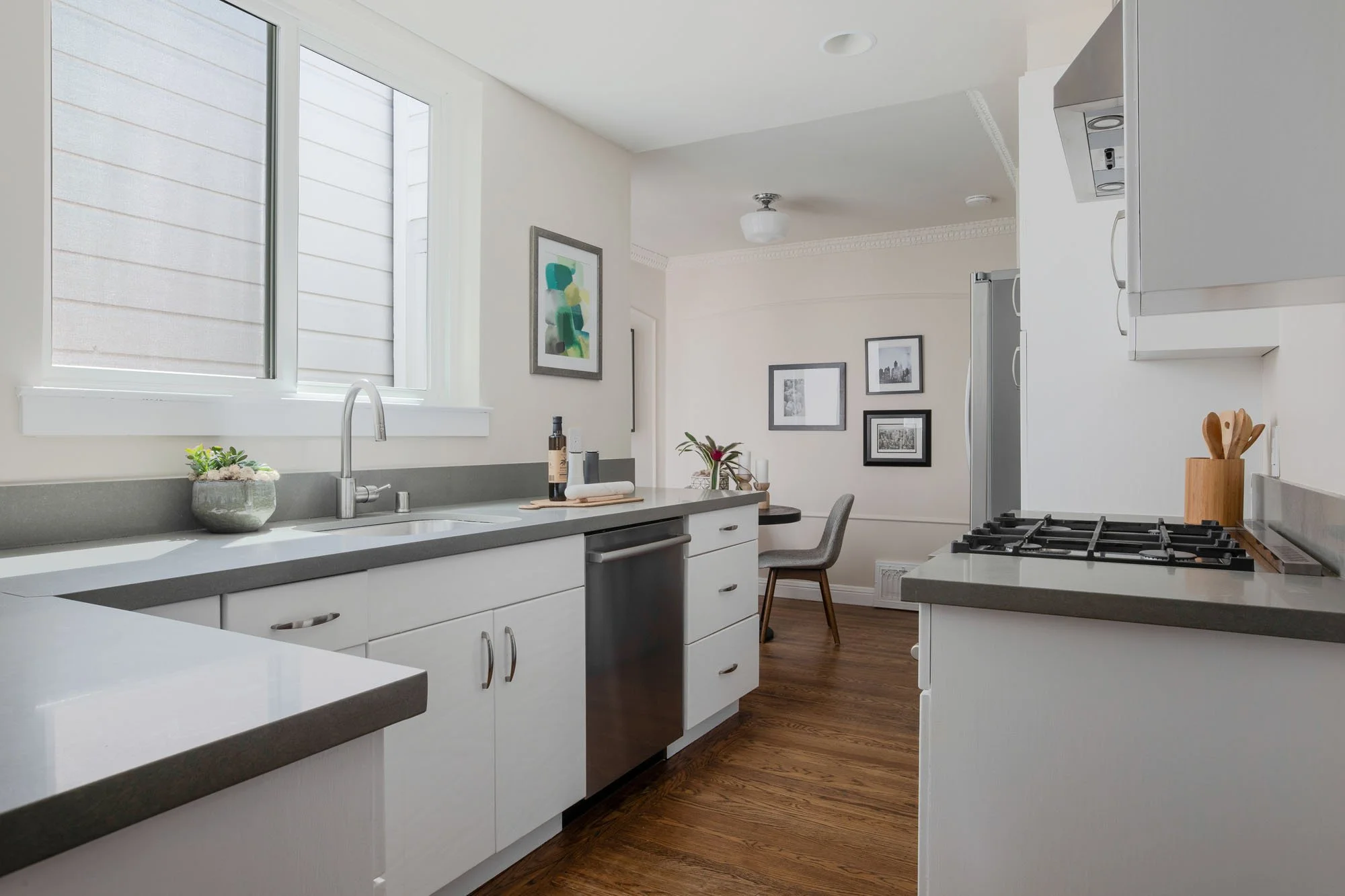 Modernized kitchen with white cabinetry, sleek grey quartz countertops, stainless steel appliances, and a bright window overlooking the Mission District.