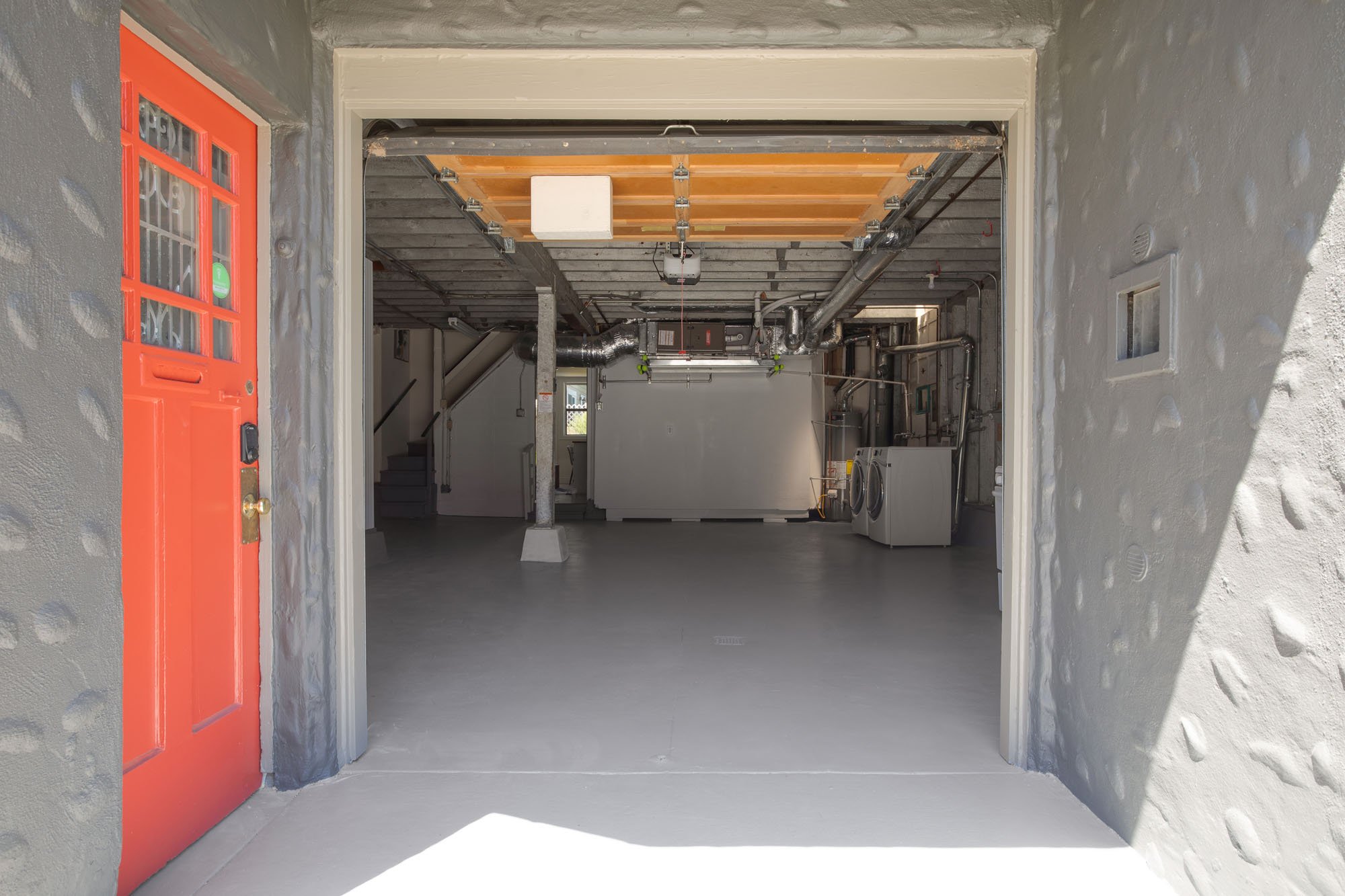 Spacious attached garage at 2872 25th Street with clean epoxy floors, laundry area with washer/dryer, and interior home access next to a vibrant red door.