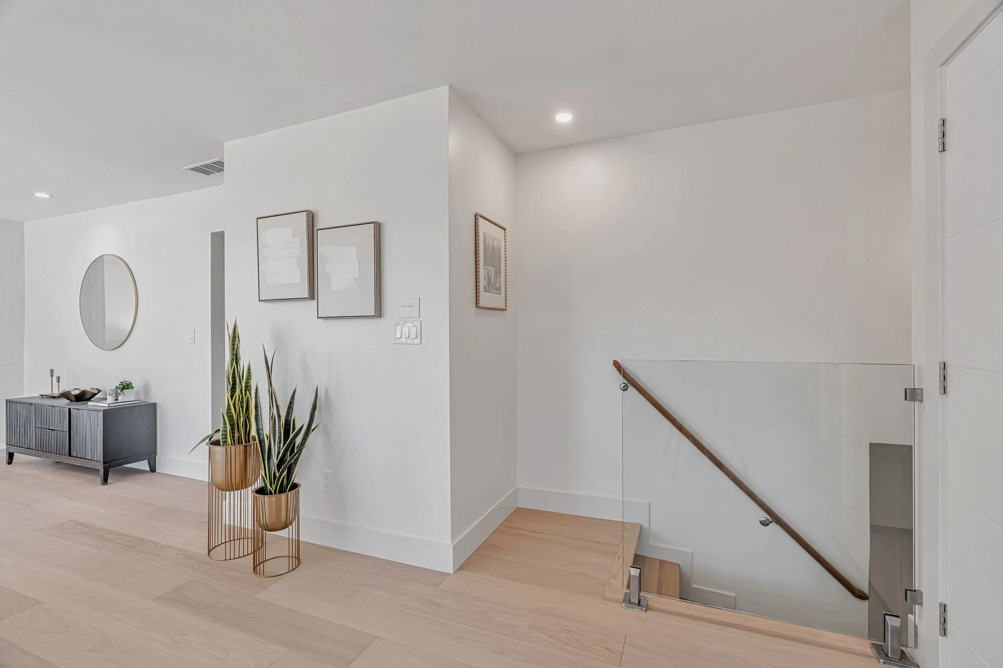 Contemporary home entryway in San Francisco with a minimalist glass and wood handrail, light oak flooring, and high-end modern staging.