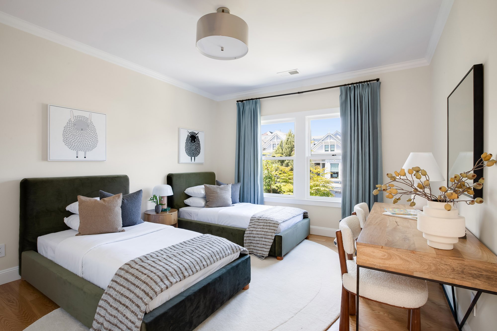 Children's bedroom at 771 Elizabeth Street in Noe Valley with two upholstered beds, a built-in desk nook, neighborhood views, and warm hardwood floors. 