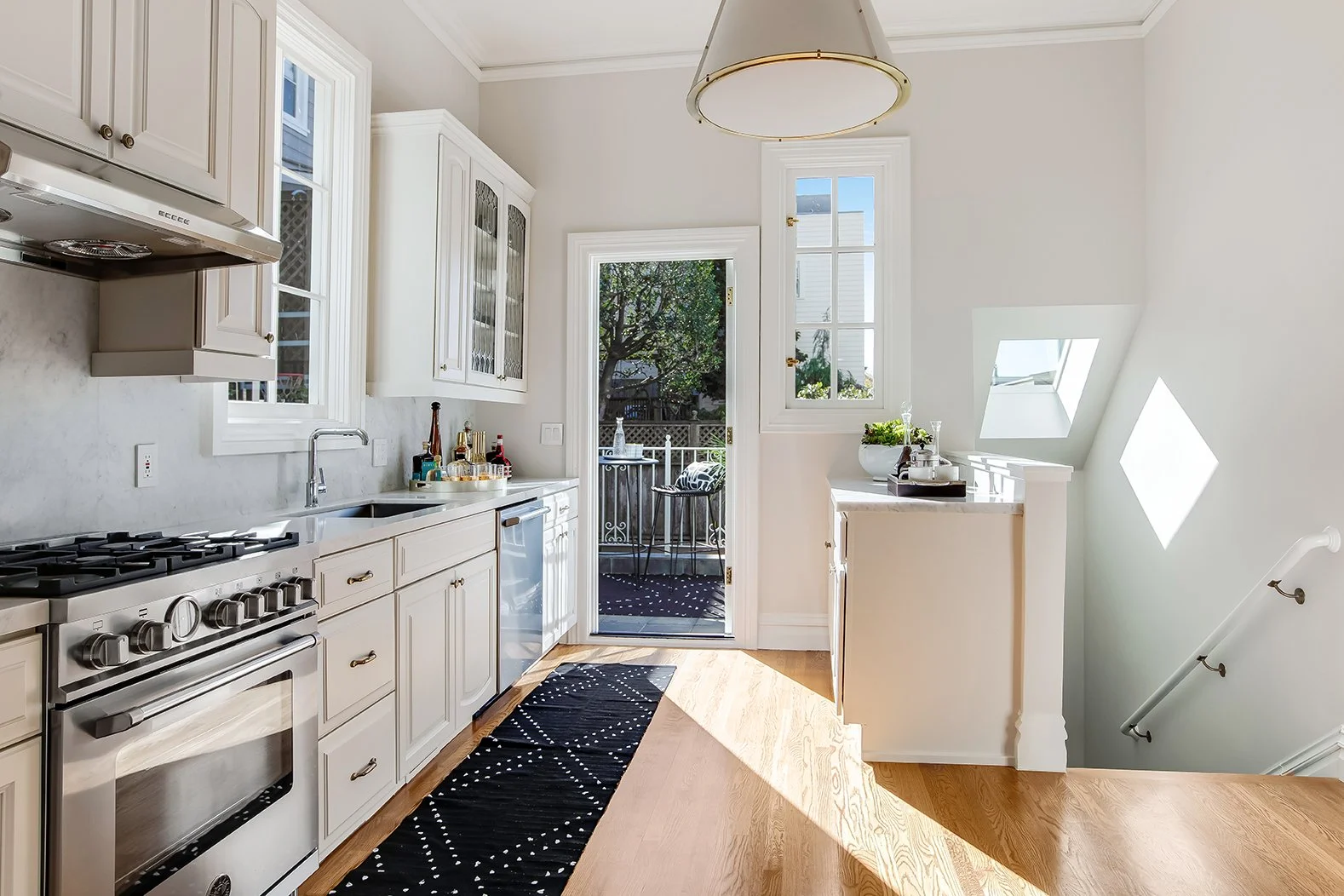 Modernized Victorian kitchen in San Francisco with marble countertops, high-end stainless steel appliances, and views of a private balcony.
