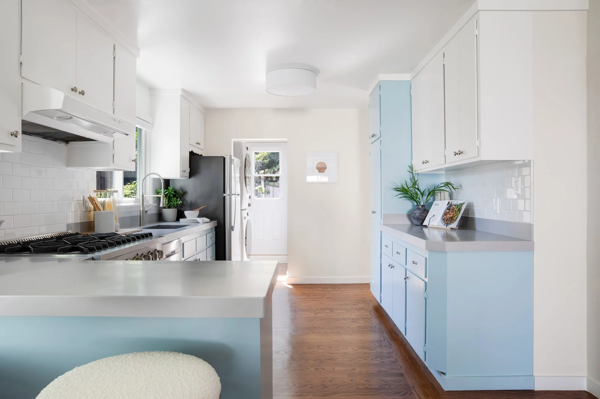 Kitchen at 465 30th Street with pantry cabinets, new hardwood floors and a stacked washer and dryer beside the door to the rear garden