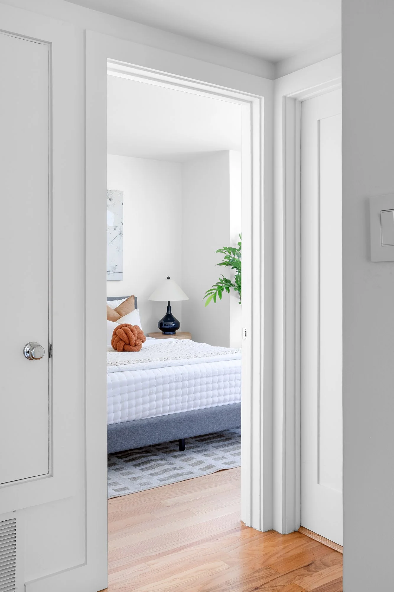 View from the hallway into the second bedroom at 932 Broderick Street #2, with hardwood floors and adjacent closet doors.