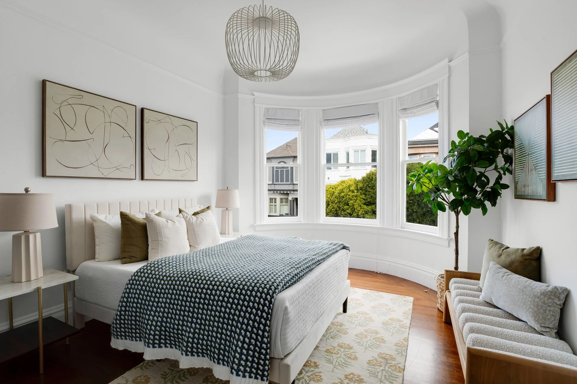 Second bedroom with original curved bay windows, Victorian crown molding, hardwood floors, and treetop views of Sacramento Street in Presidio Heights Victorian flat, San Francisco