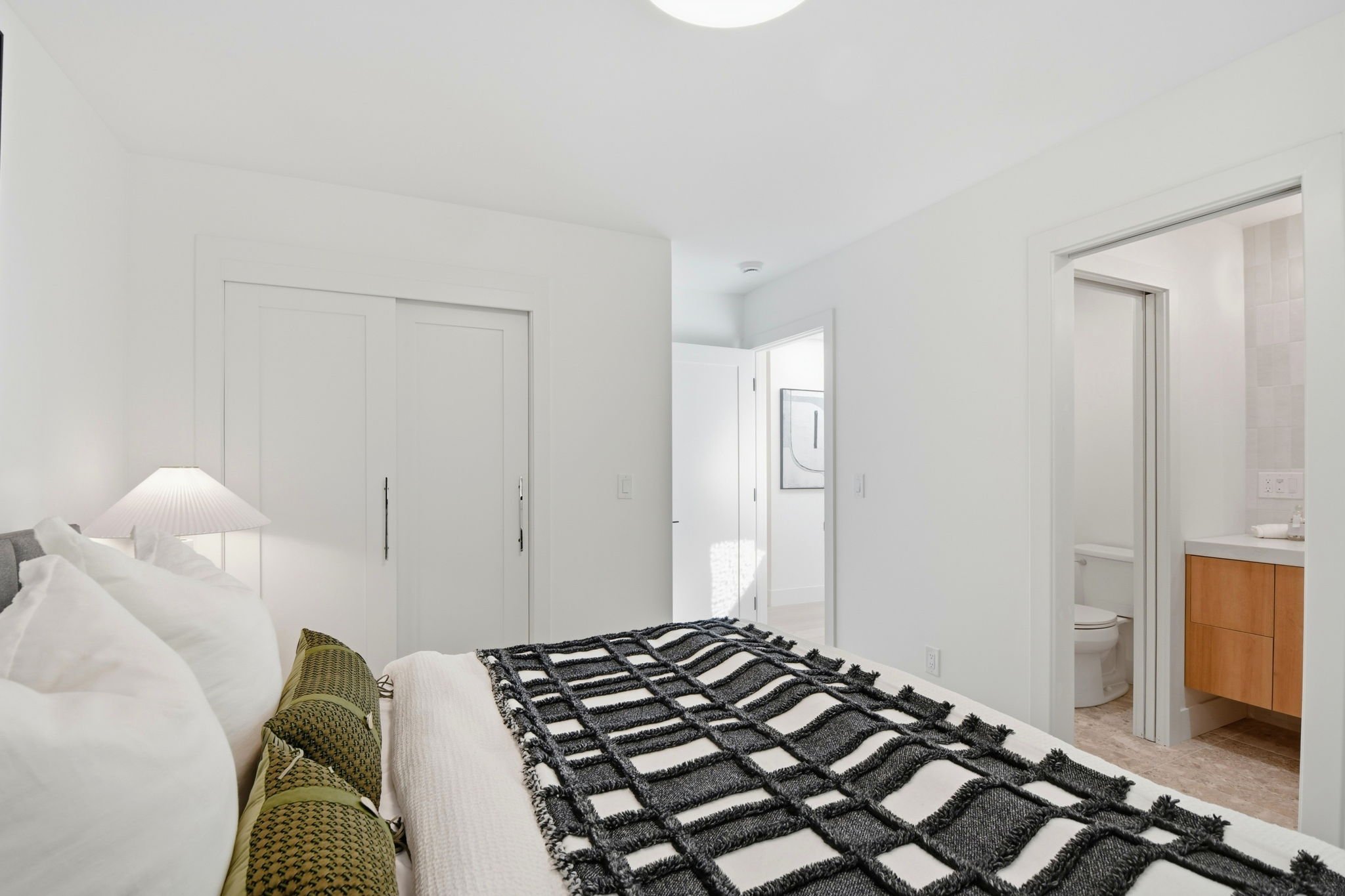 Seamless flow from the primary bedroom to the spa-like ensuite bathroom and built-in closet storage in a modern San Francisco home.