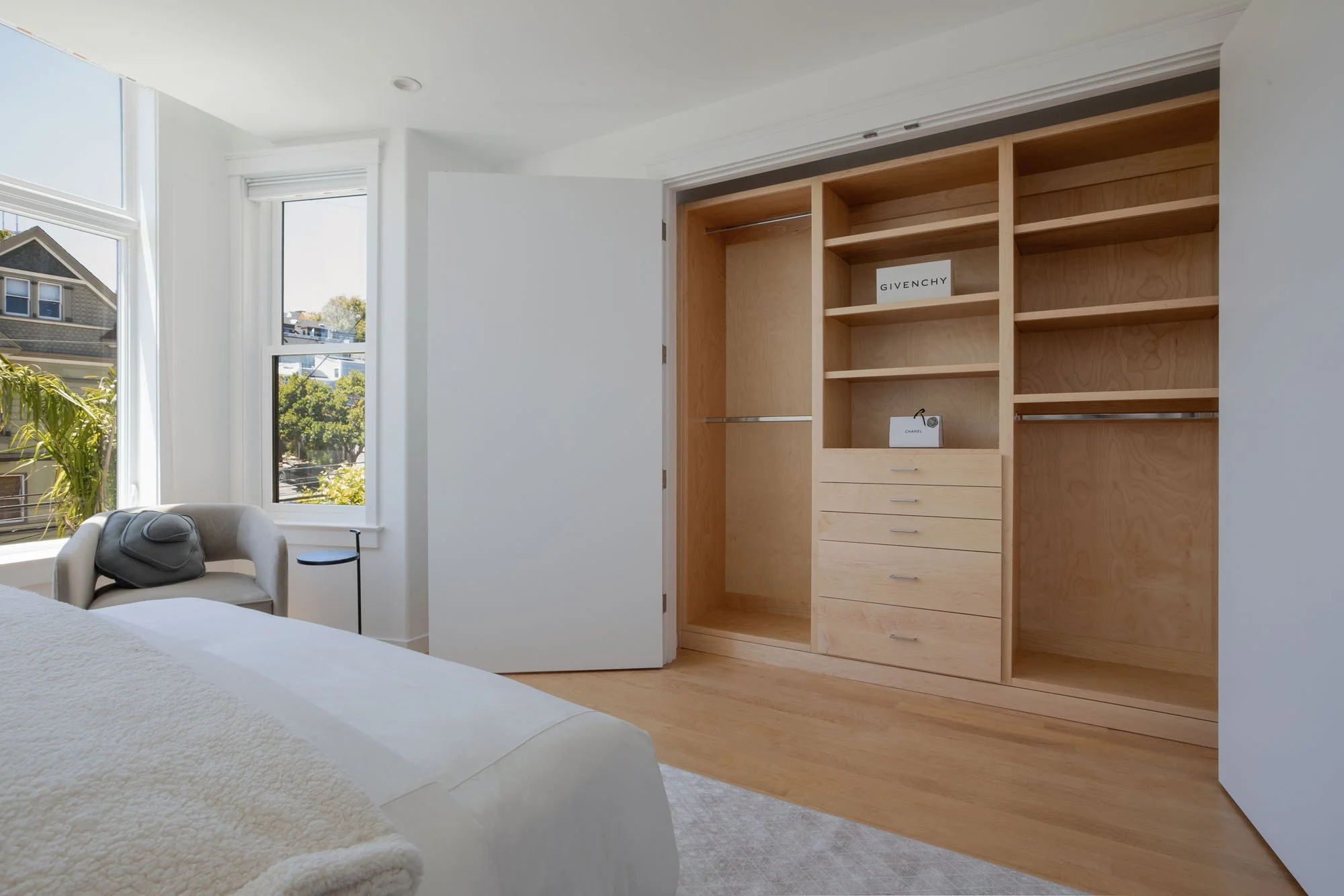 Luxury bedroom featuring a large custom built-in walk-in closet with light wood finishes, adjustable shelving, and integrated dresser drawers.
