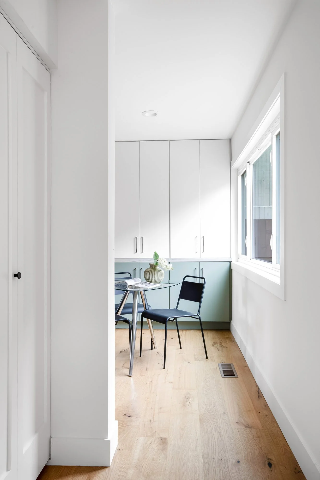 Kitchen eating area at 75 Aloha Avenue in Golden Gate Heights, San Francisco, with sage-green and white cabinetry lining the wall beneath a window.