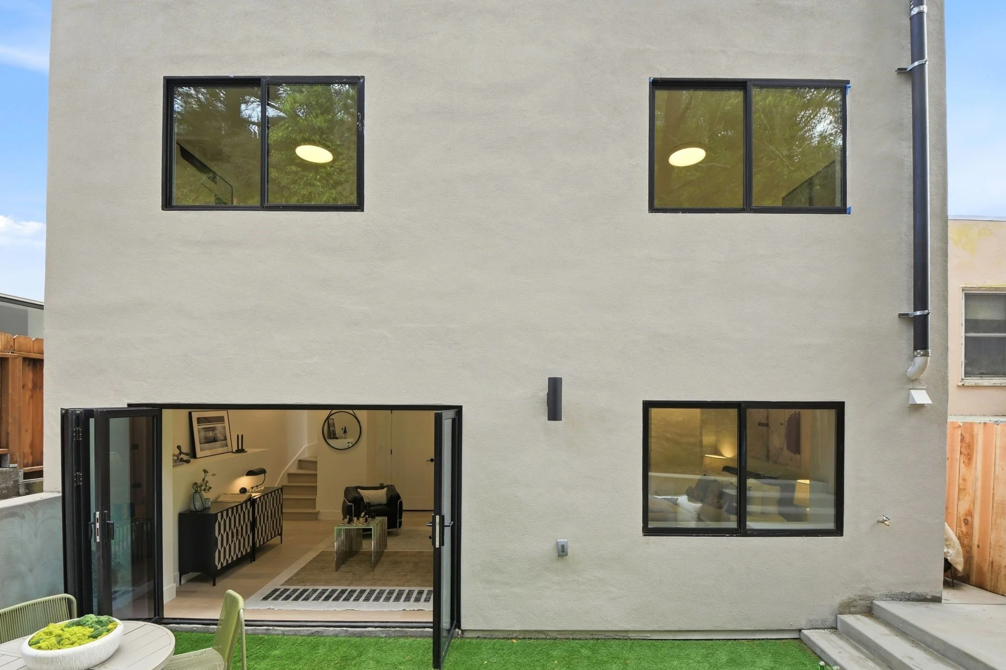 Rear view of a modernist San Francisco home in Midtown Terrace, showcasing expansive glass doors that open to a private, sun-drenched terrace.
