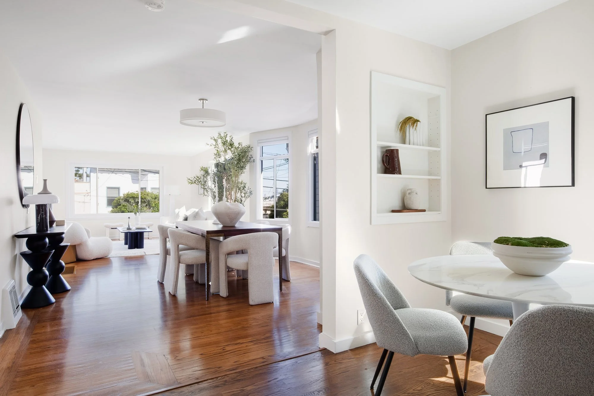 View from the eat-in kitchen through the dining area to the living room at 465 30th Street, showing the open floor plan, hardwood floors and a built-in display niche
