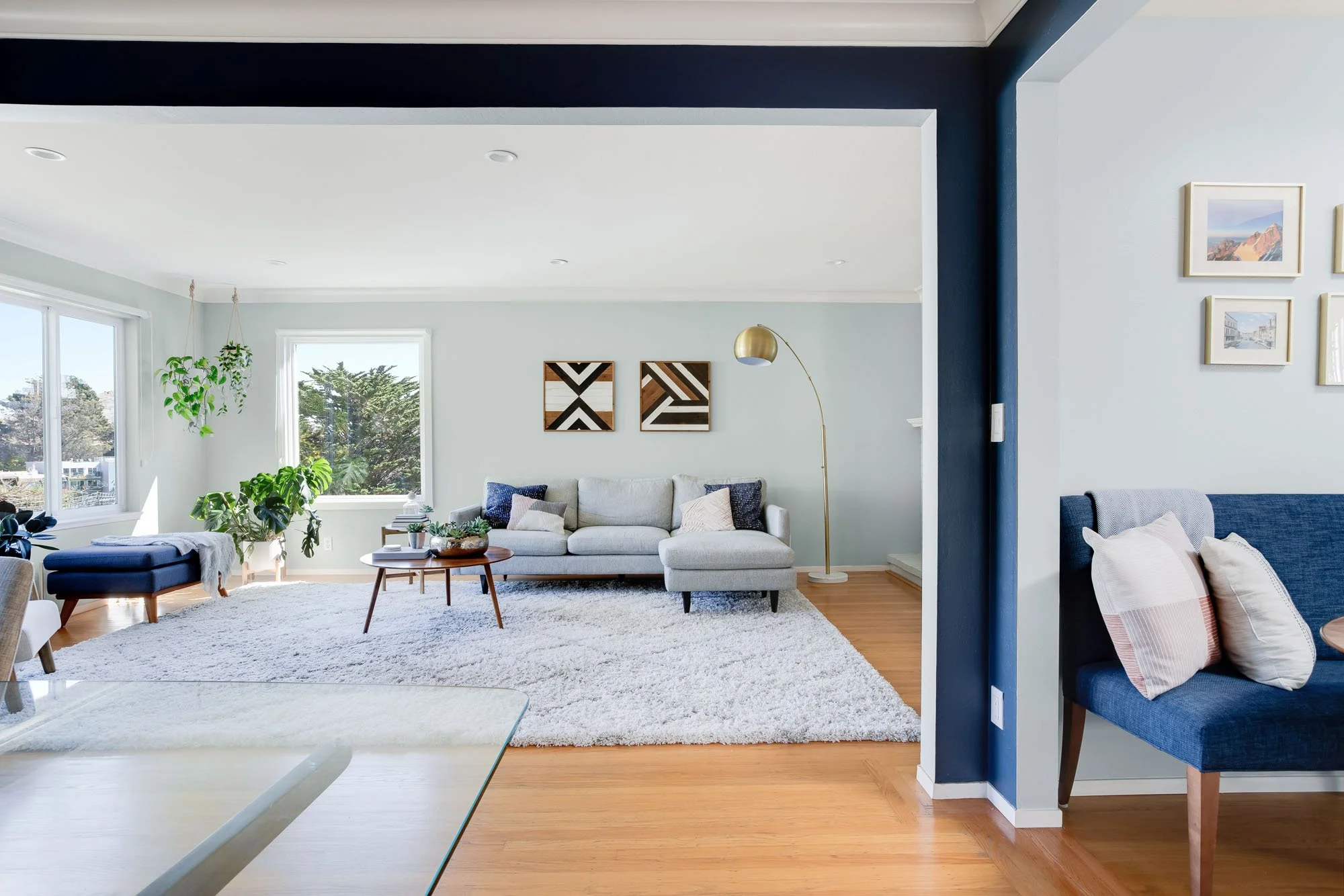 A wide-angle view from the dining area looking back into the living room, highlighting the flow of the hardwood floors and the contrast between the navy blue and light gray walls.