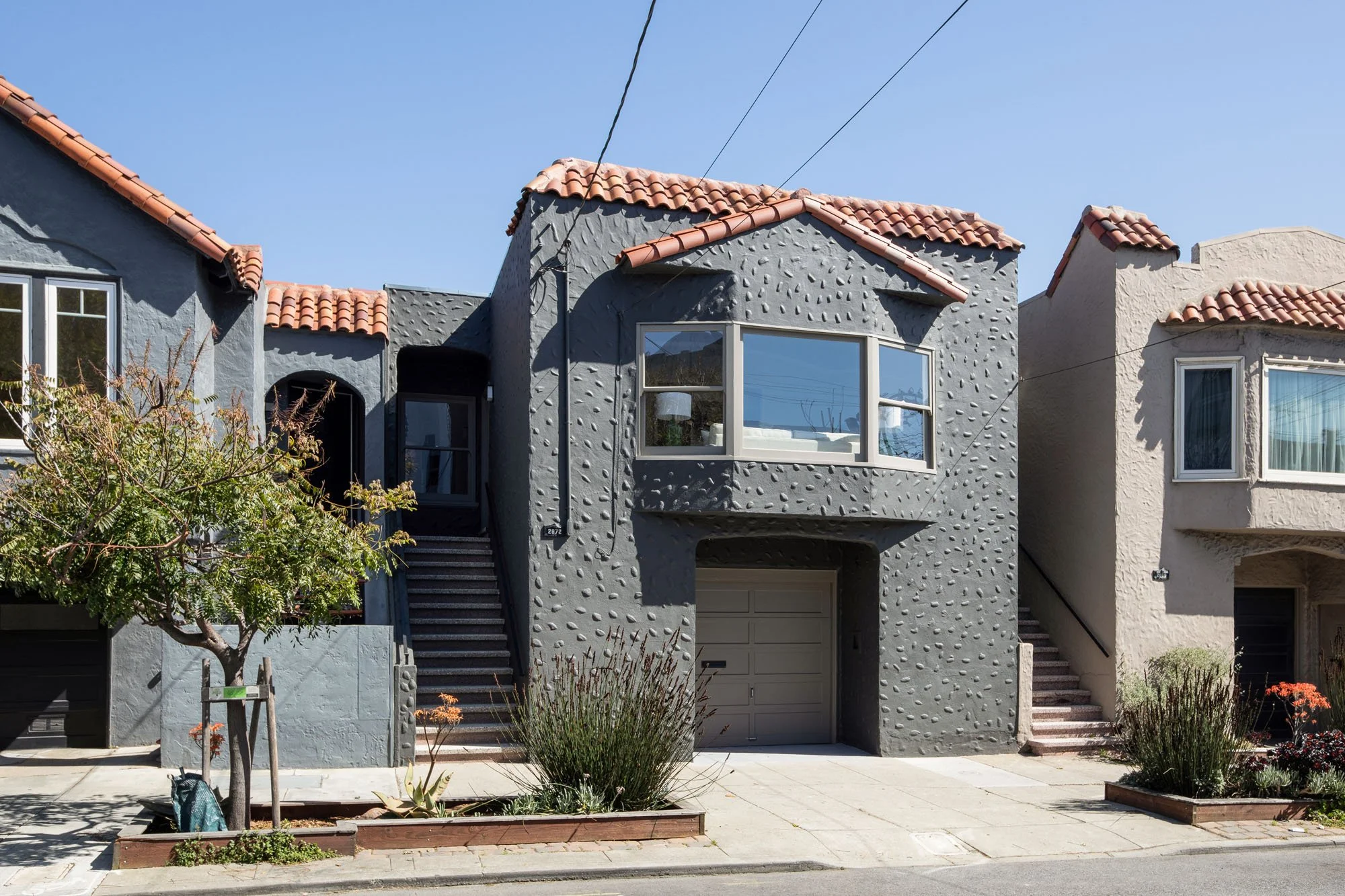 Exterior view of 2872 25th Street in San Francisco’s Mission District featuring a unique charcoal pebble-dash stucco facade and Mediterranean red tile roof.