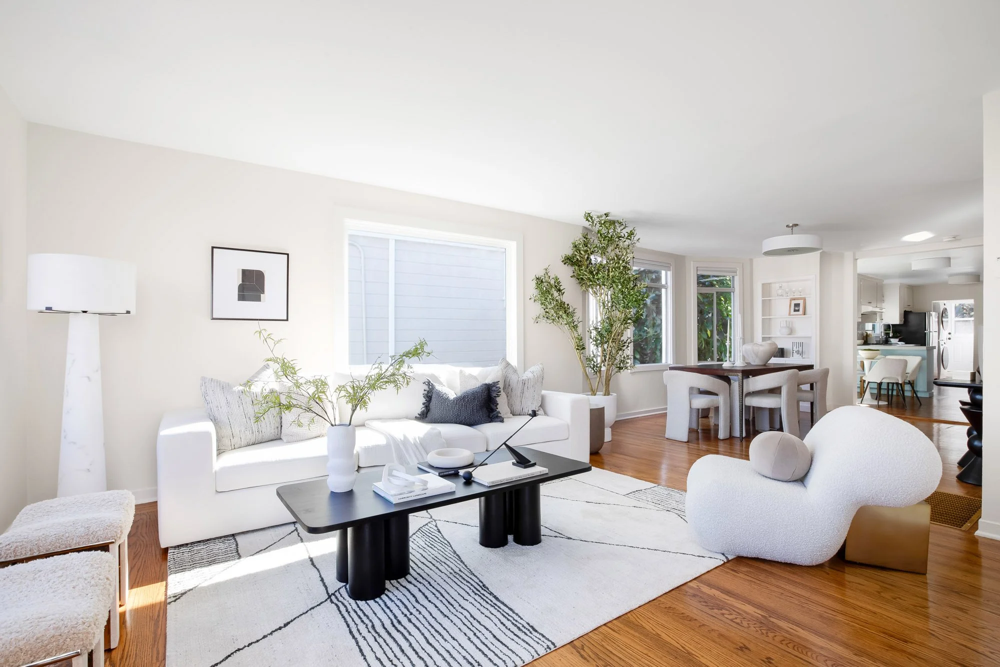 Open living and dining room at 465 30th Street with hardwood floors, a large picture window, built-in shelving and a view through the dining room to the eat-in kitchen
