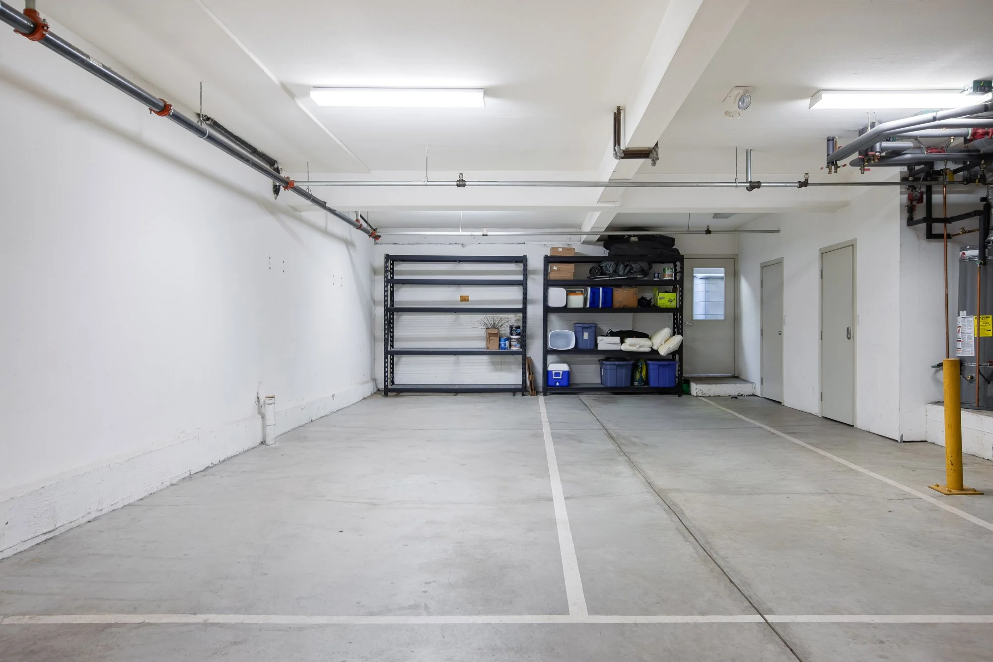 Secure shared garage at 2172 Fell Street San Francisco with two dedicated parking spaces, concrete floors, metal storage shelving, and utility room access — a rare amenity in the Panhandle neighborhood