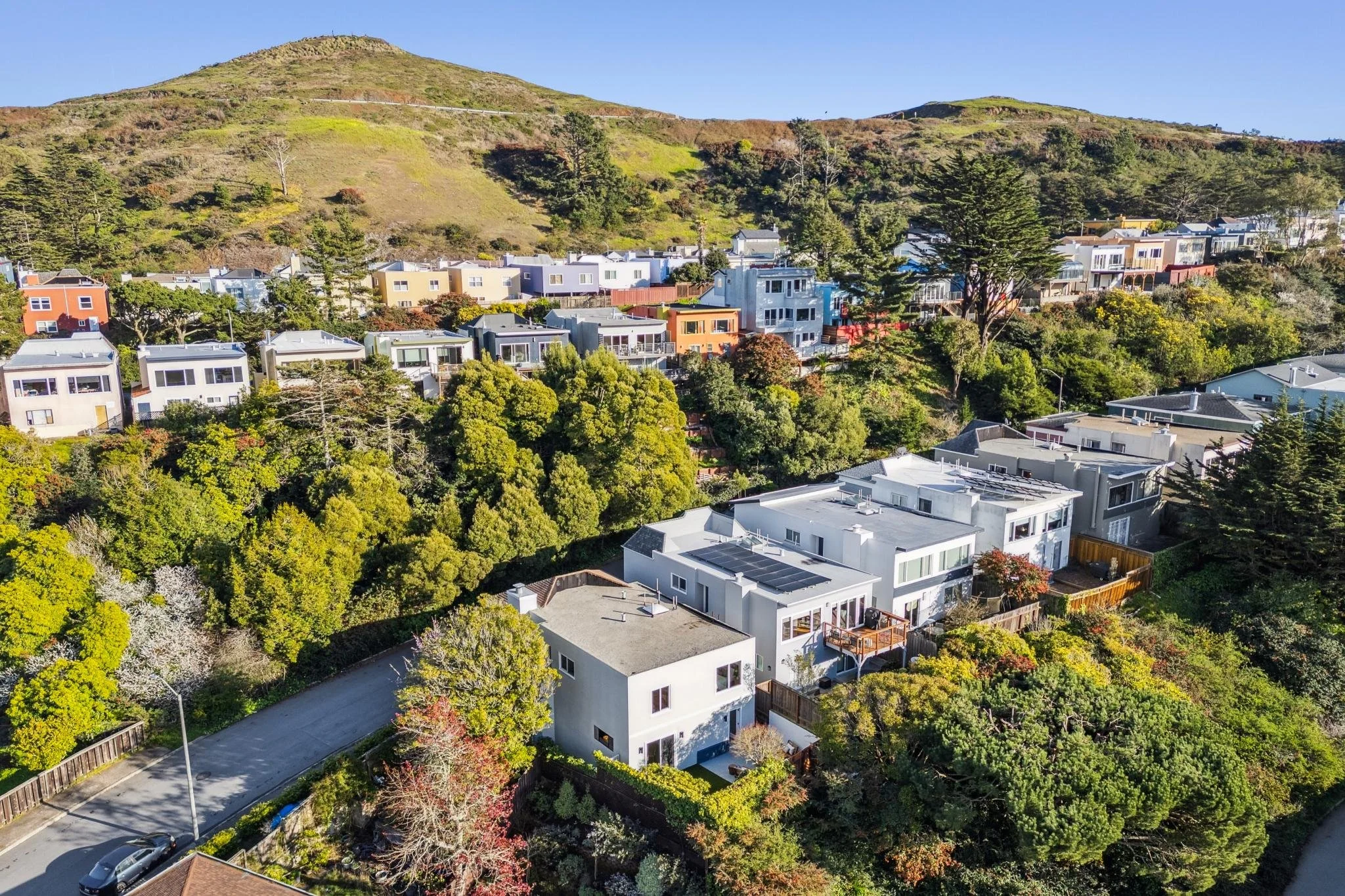 Aerial perspective of a hillside San Francisco neighborhood, highlighting a renovated modern home among vibrant coastal greenery.