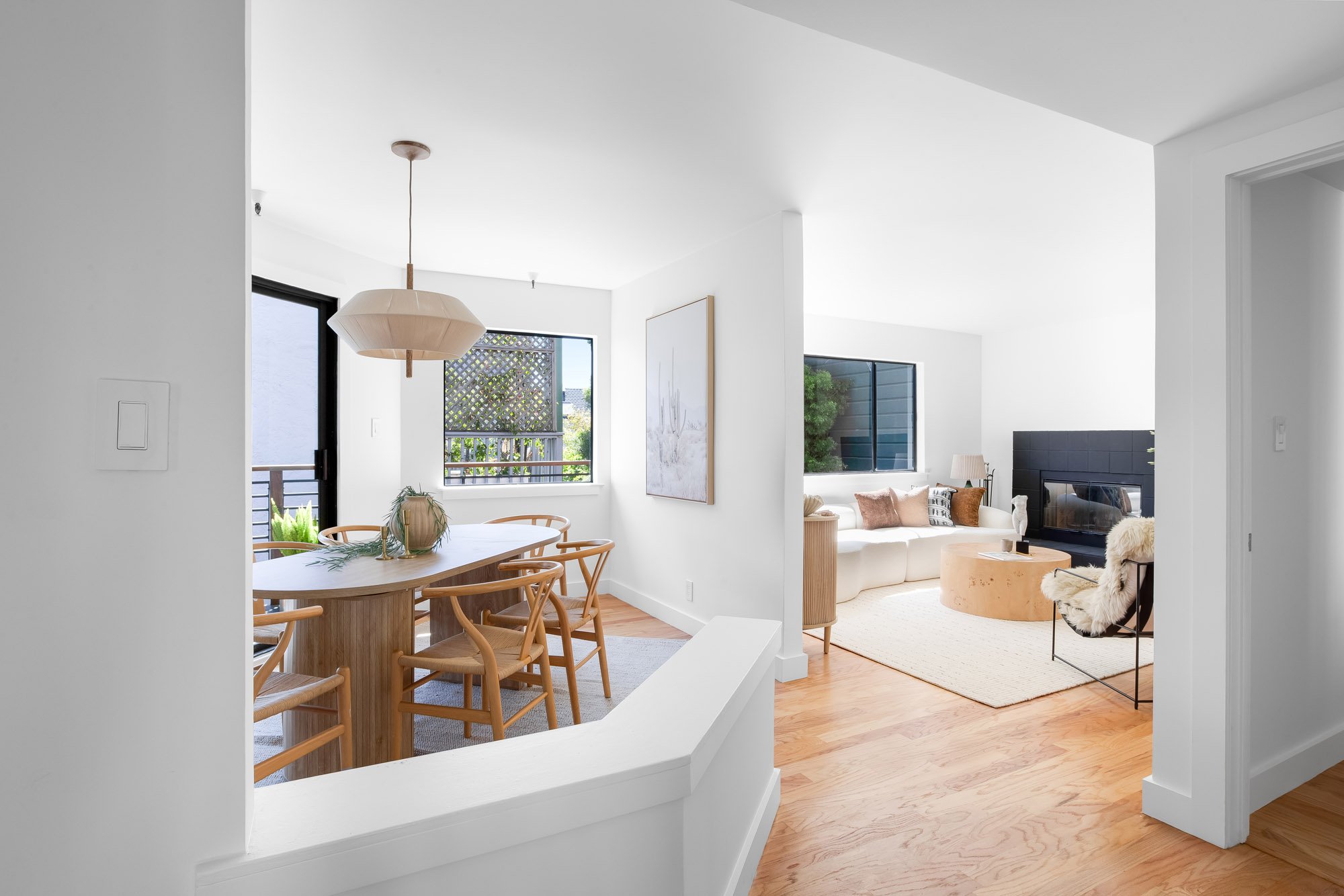 Open-concept living and dining area at 932 Broderick Street #2 with hardwood floors, a tiled fireplace, and a balcony off the dining room.