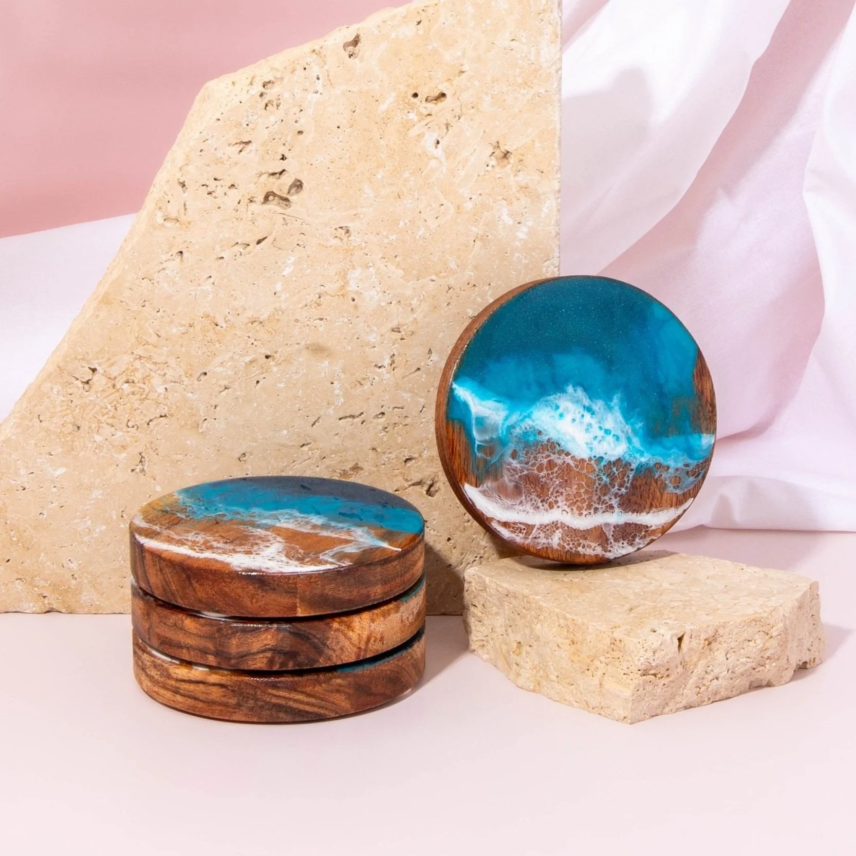 Artistic resin and wood cutting boards with ocean and marble designs, displayed on a wooden surface coasters