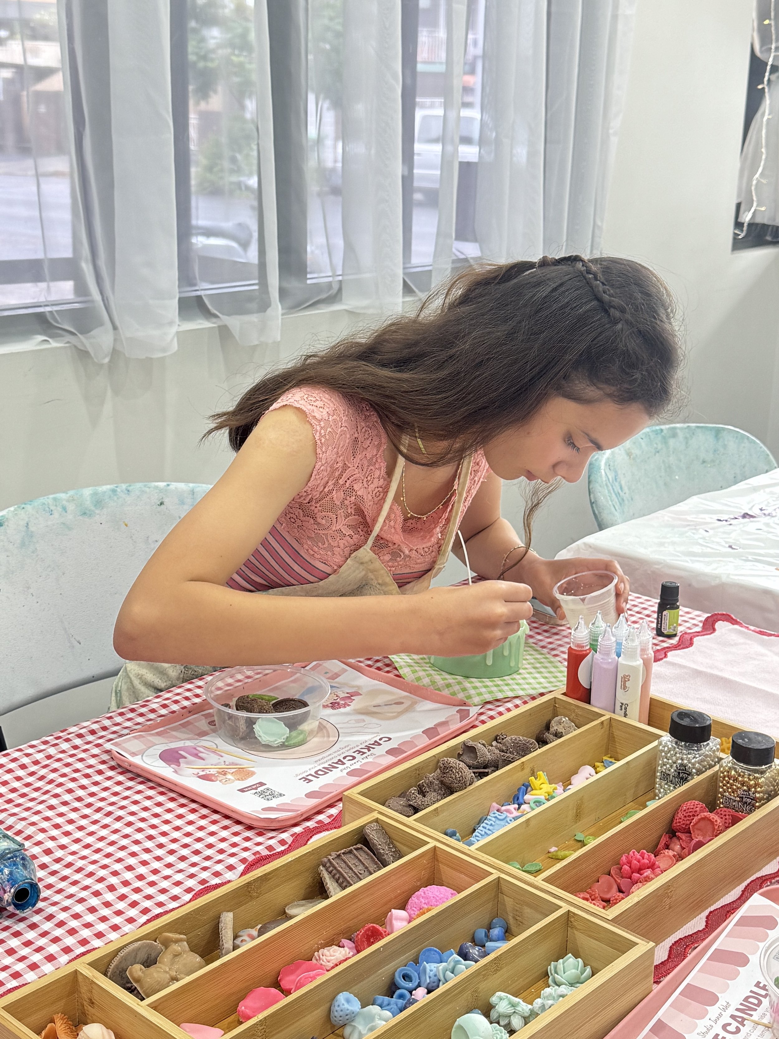Girl crafting with various colorful materials on a table indoors.