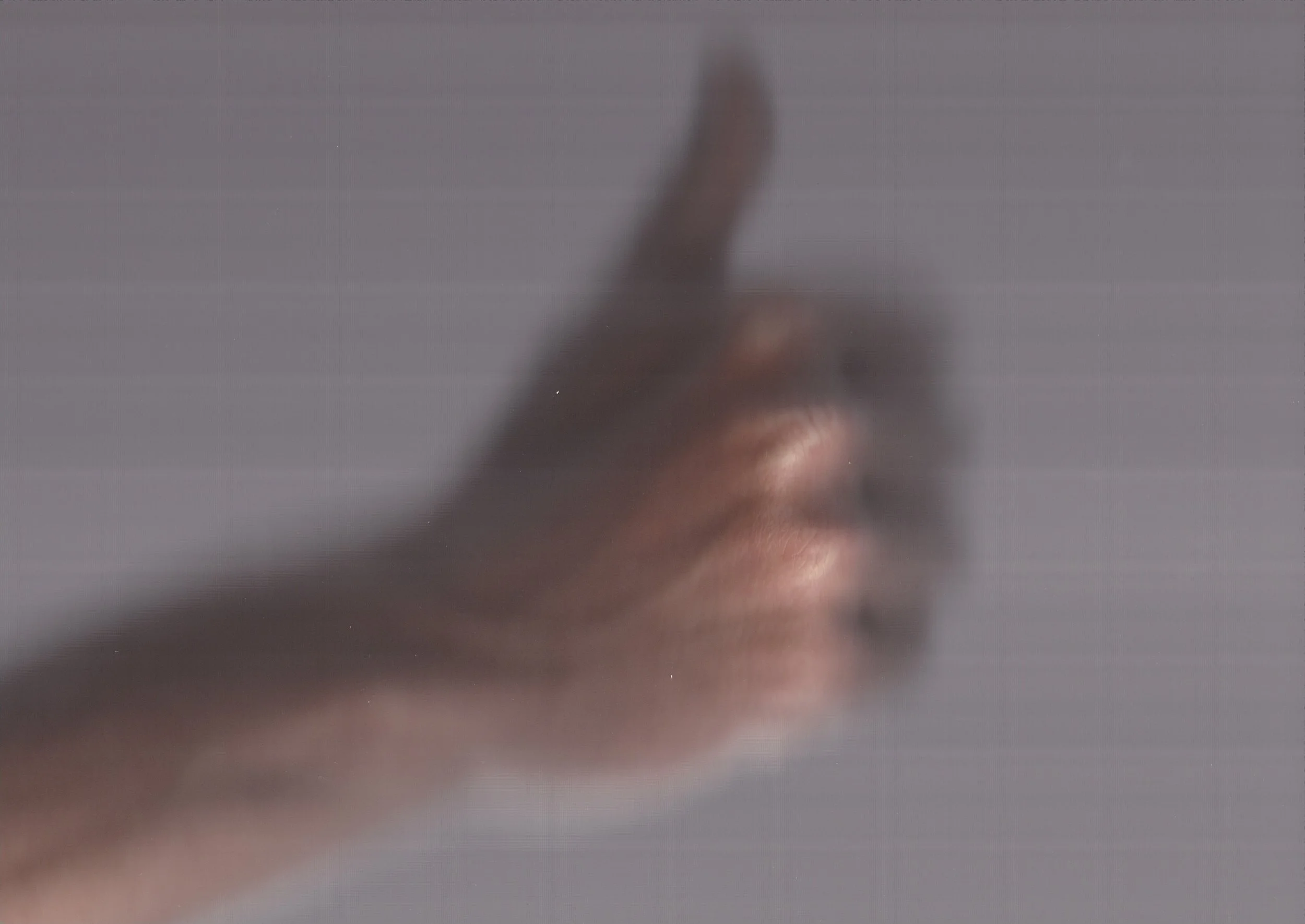 Close-up of a person's lips and finger, with the finger touching the lips, against a blurred background.