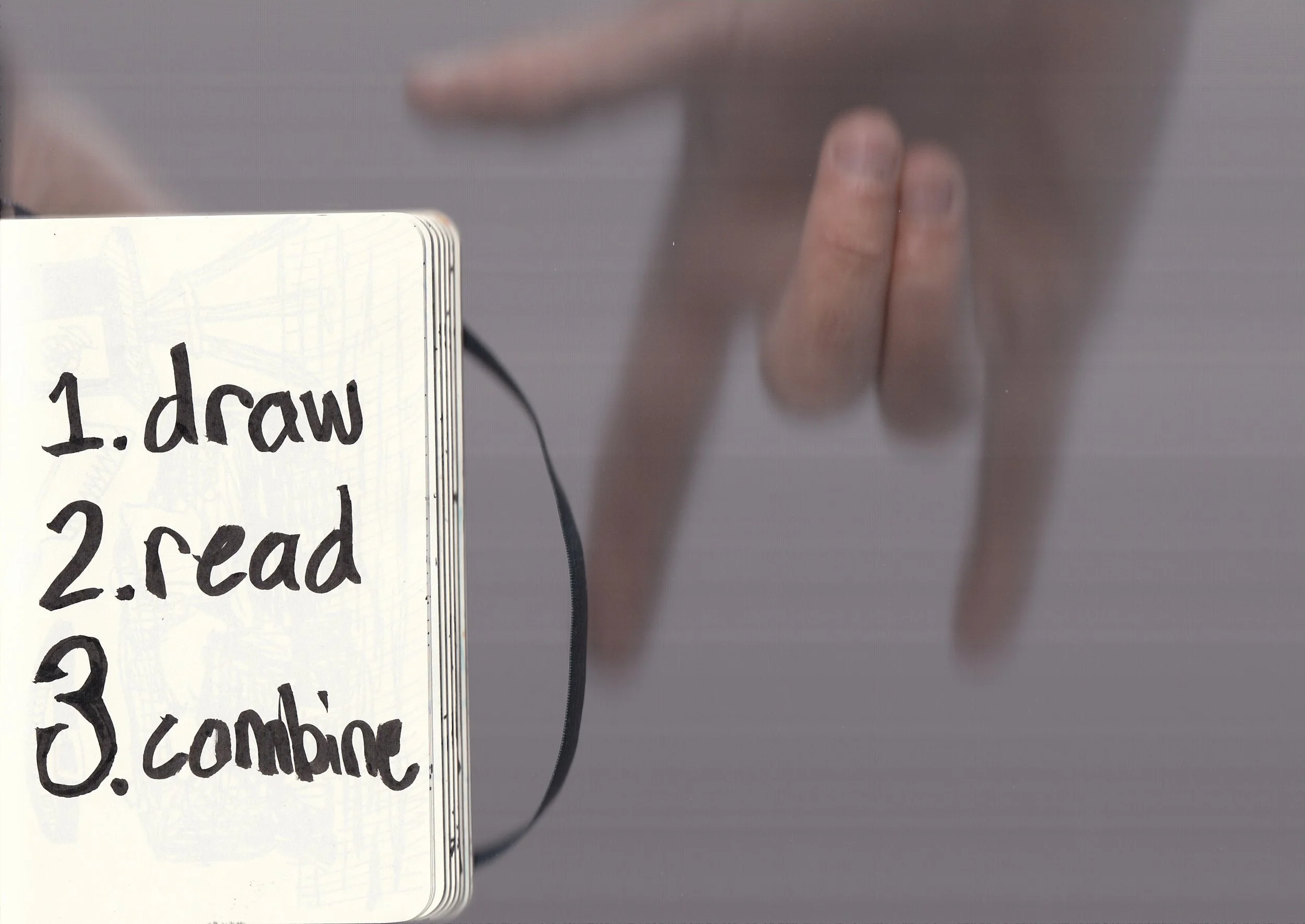 Close-up of a whiteboard with handwritten text that says '1. draw', with a person's hand holding a marker in the background, slightly out of focus.