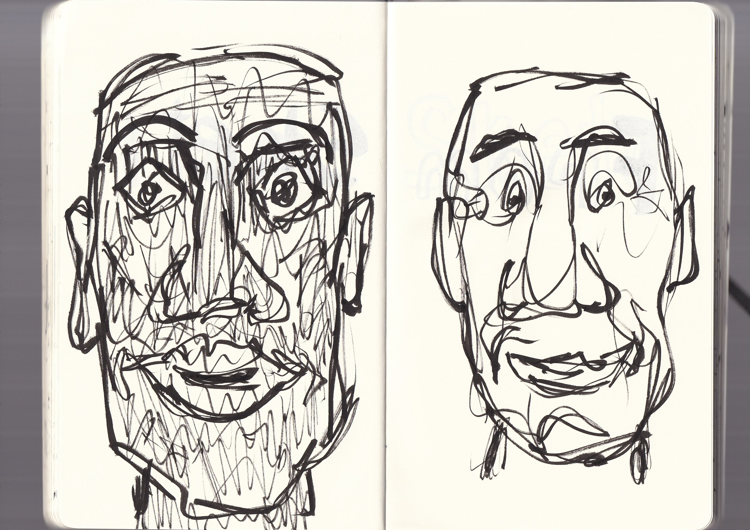 A black ink sketch of two human faces, one on each page of an open sketchbook. The drawing style is abstract and expressive with loose, energetic lines.